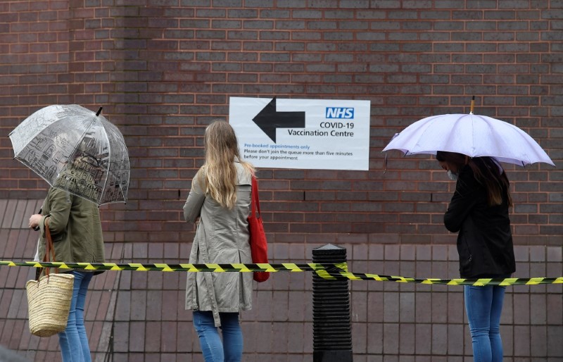 People queue in the rain to receive a COVID-19 vaccination amid the spread of the coronavirus disease pandemic, London, Britain, June 18, 2021. REUTERS/Toby Melville