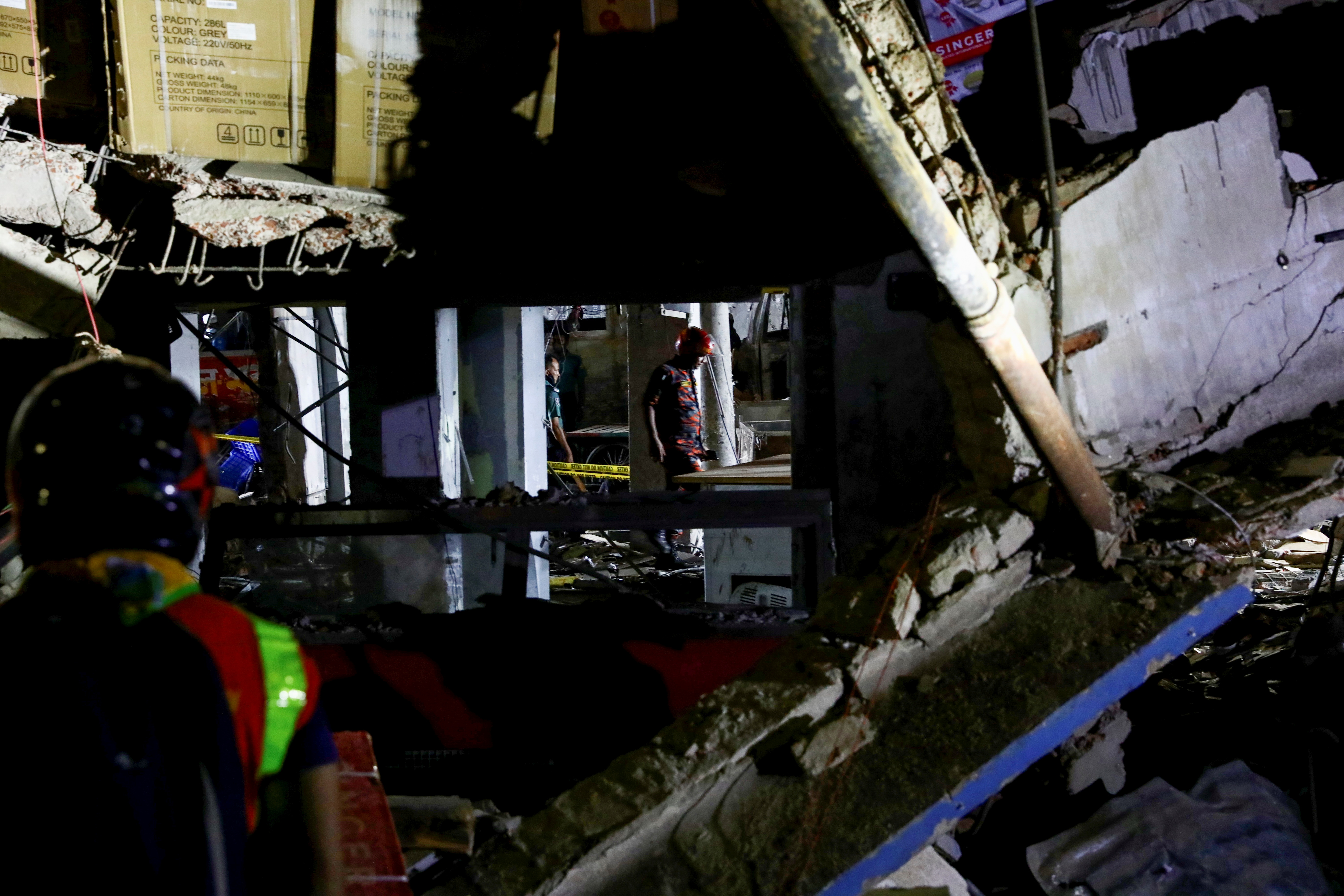 Rescue workers inspect the site after a blast in a shop that killed several people in Dhaka