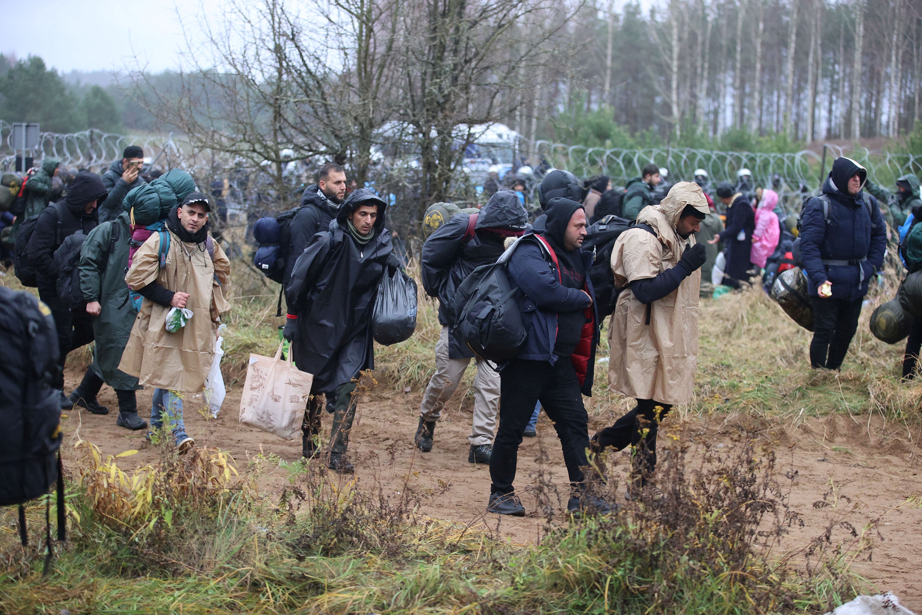 Migrants gather near a barbed wire fence in an attempt to cross the border with Poland in the Grodno region, Belarus November 8, 2021. Leonid Scheglov/BelTA/Handout via REUTERS 