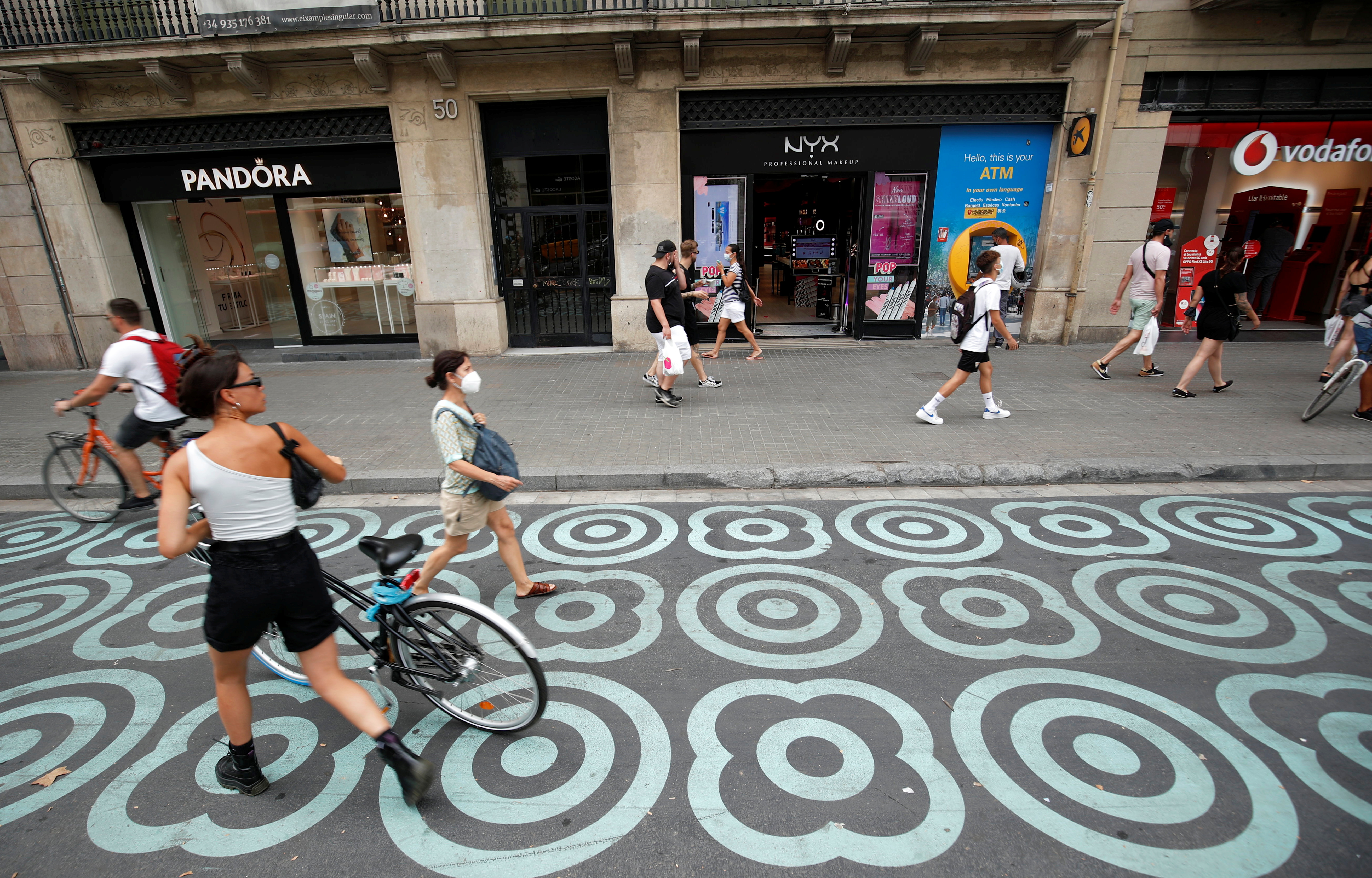 People walk by a pedestrian zone painted in blue at Pelai street in Barcelona