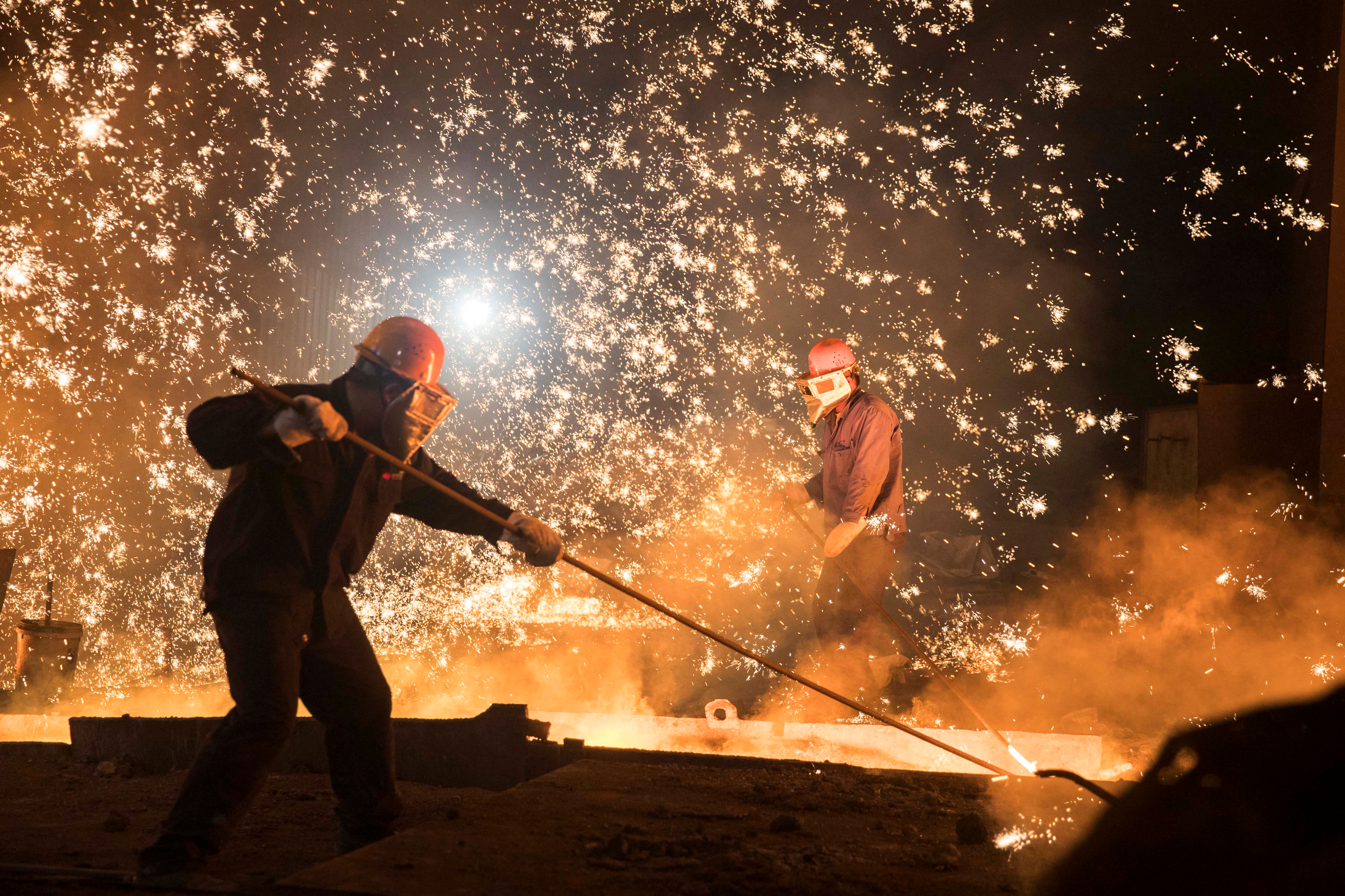 Laborers work at a steel plant of Shandong Iron & Steel Group in Jinan