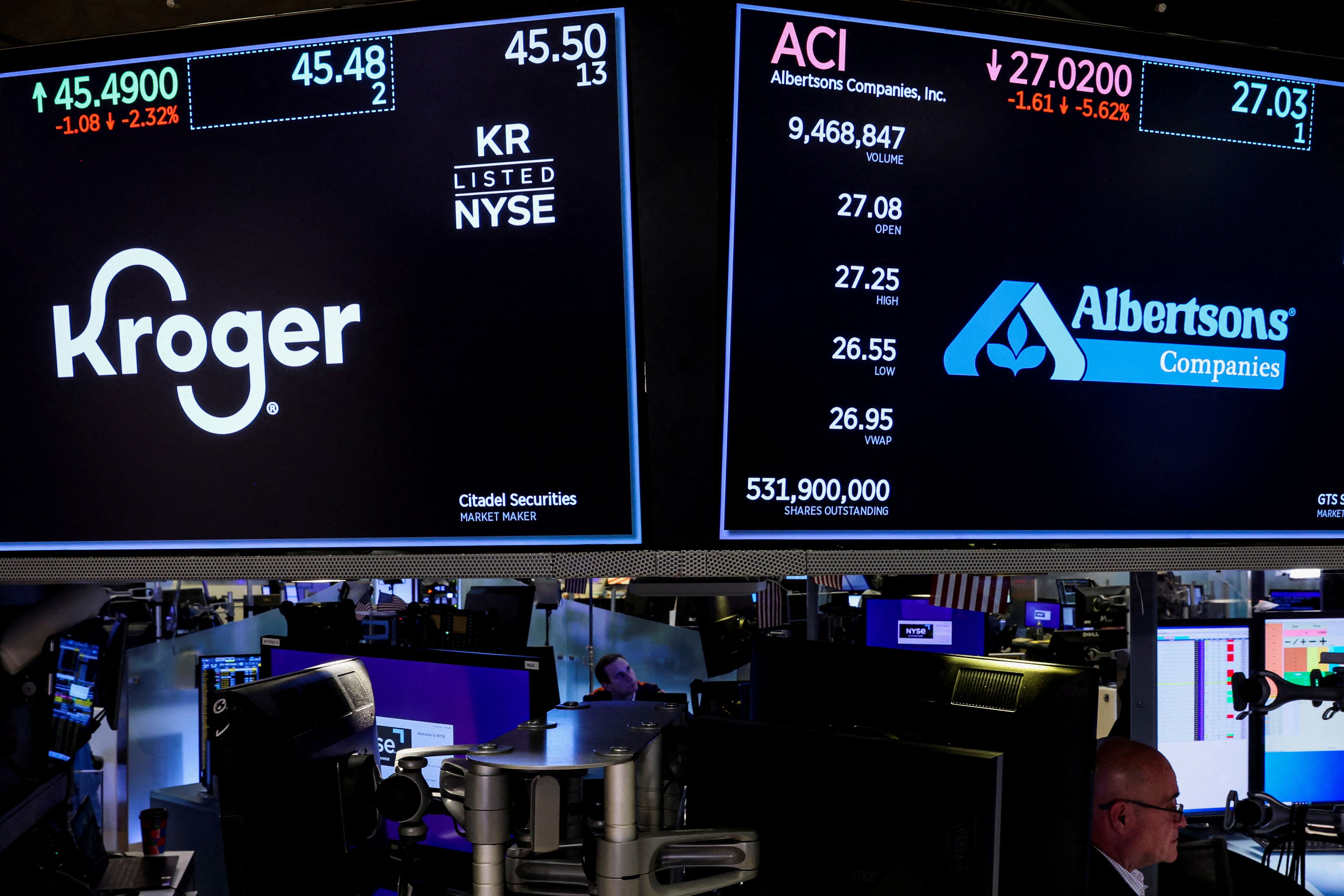 Traders work as screens display the trading information for Kroger and Albertsons on the floor of the NYSE in New York