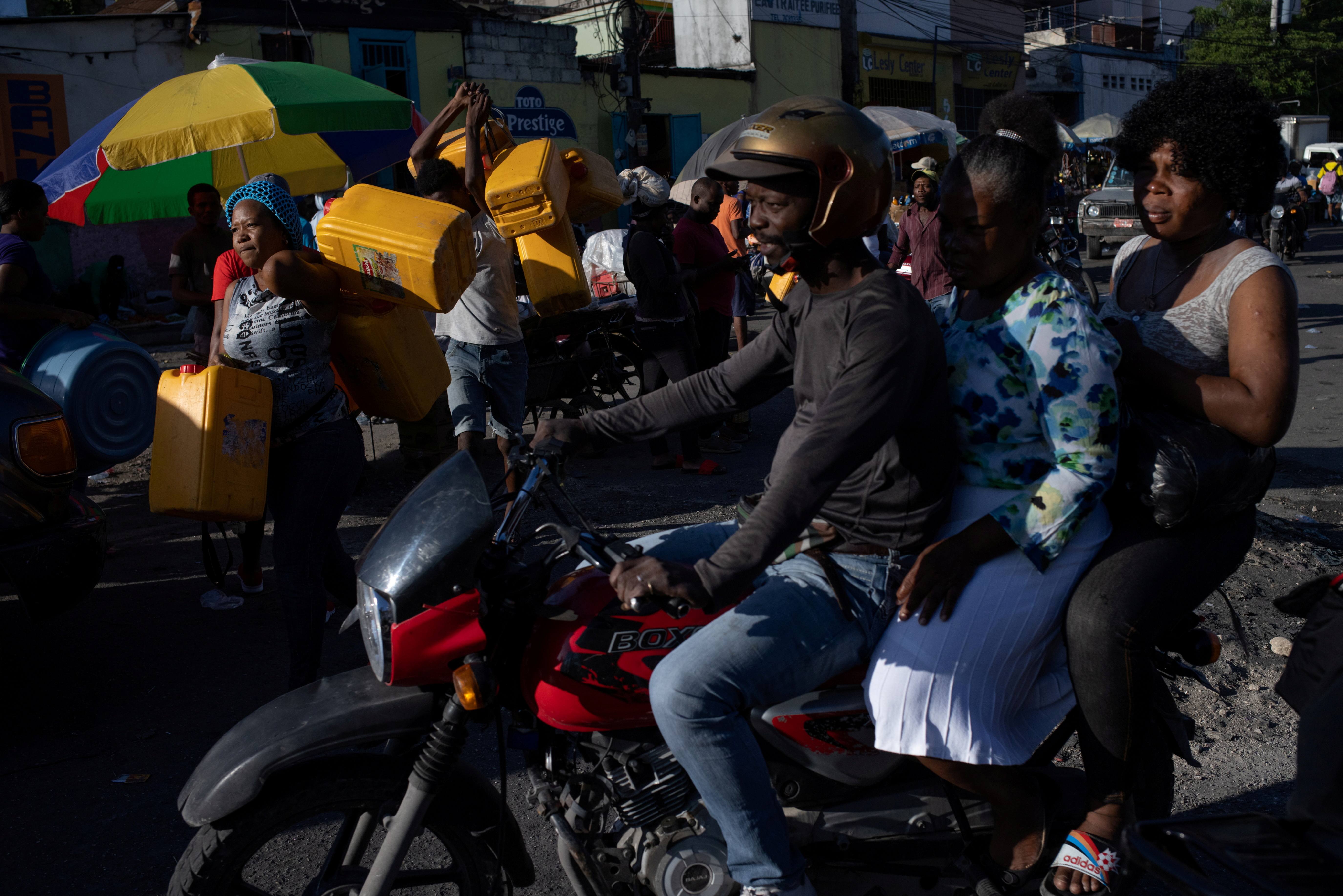 A motorbike passes by as locals carry containers, used for oil and gasoline, during fuel shortages in Port-au-Prince, Haiti October 24, 2021.  REUTERS/Adrees Latif