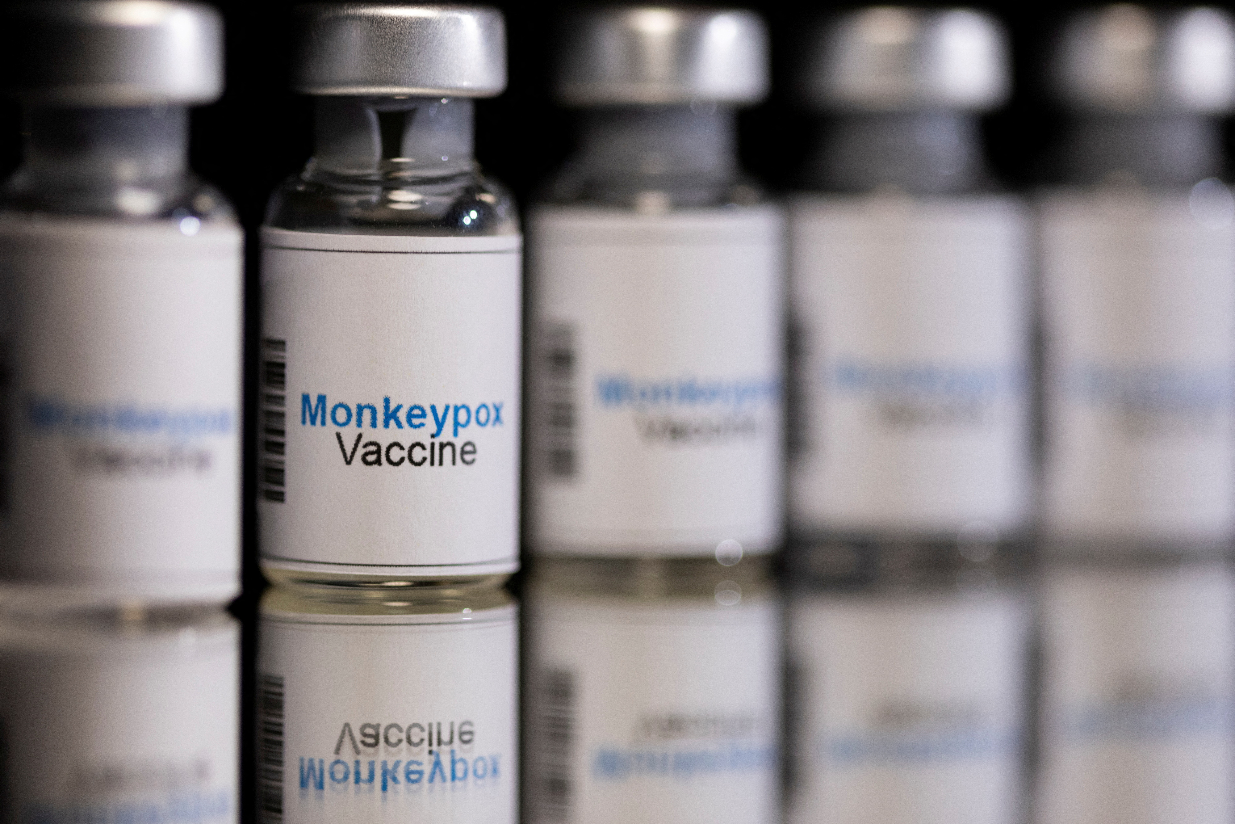 Illustration shows mock-up vials labeled "Monkeypox vaccine"