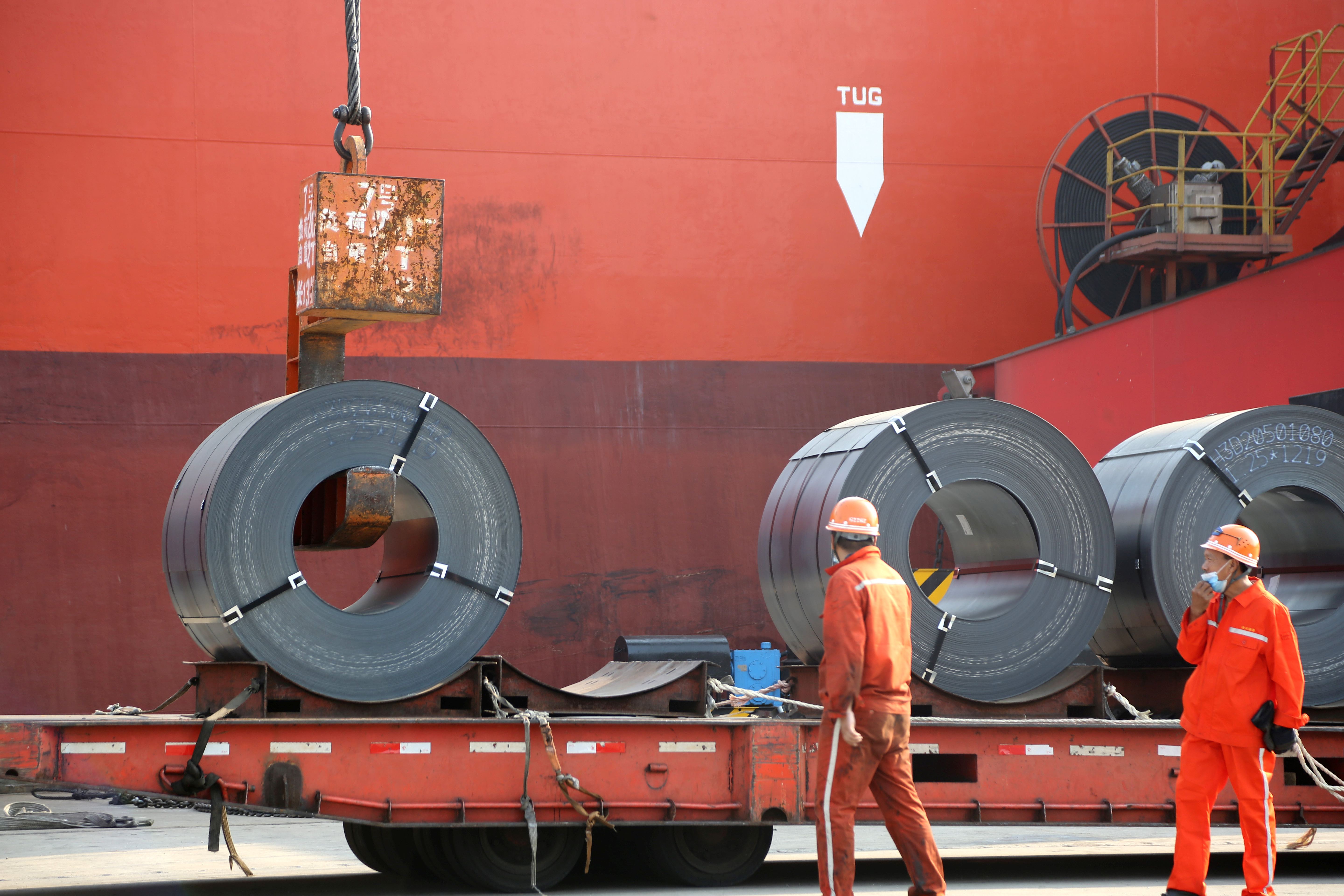 Workers load steel products for export to a cargo ship at a port in Lianyungang