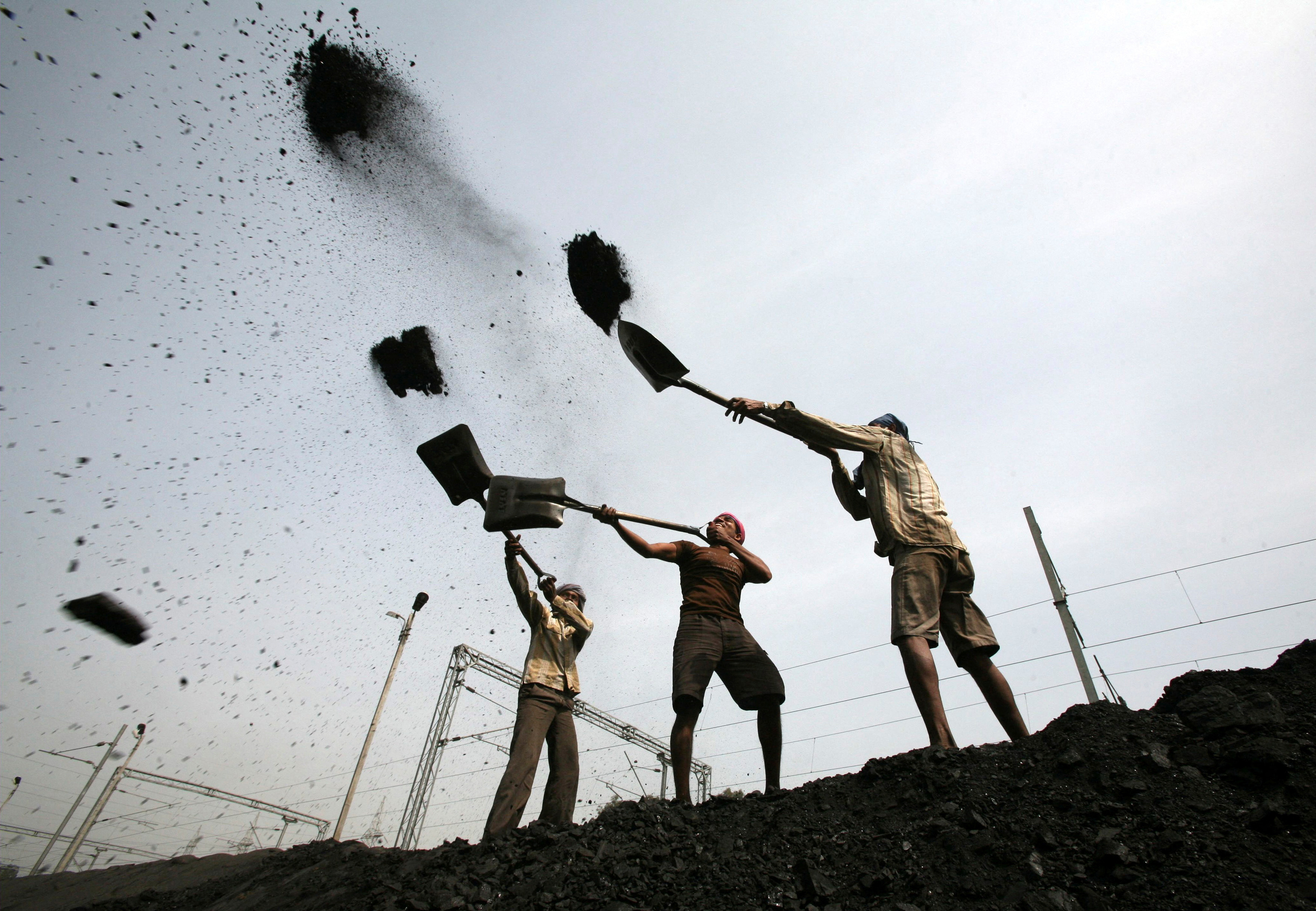 Labourers load coal on trucks on the outskirts of Jammu