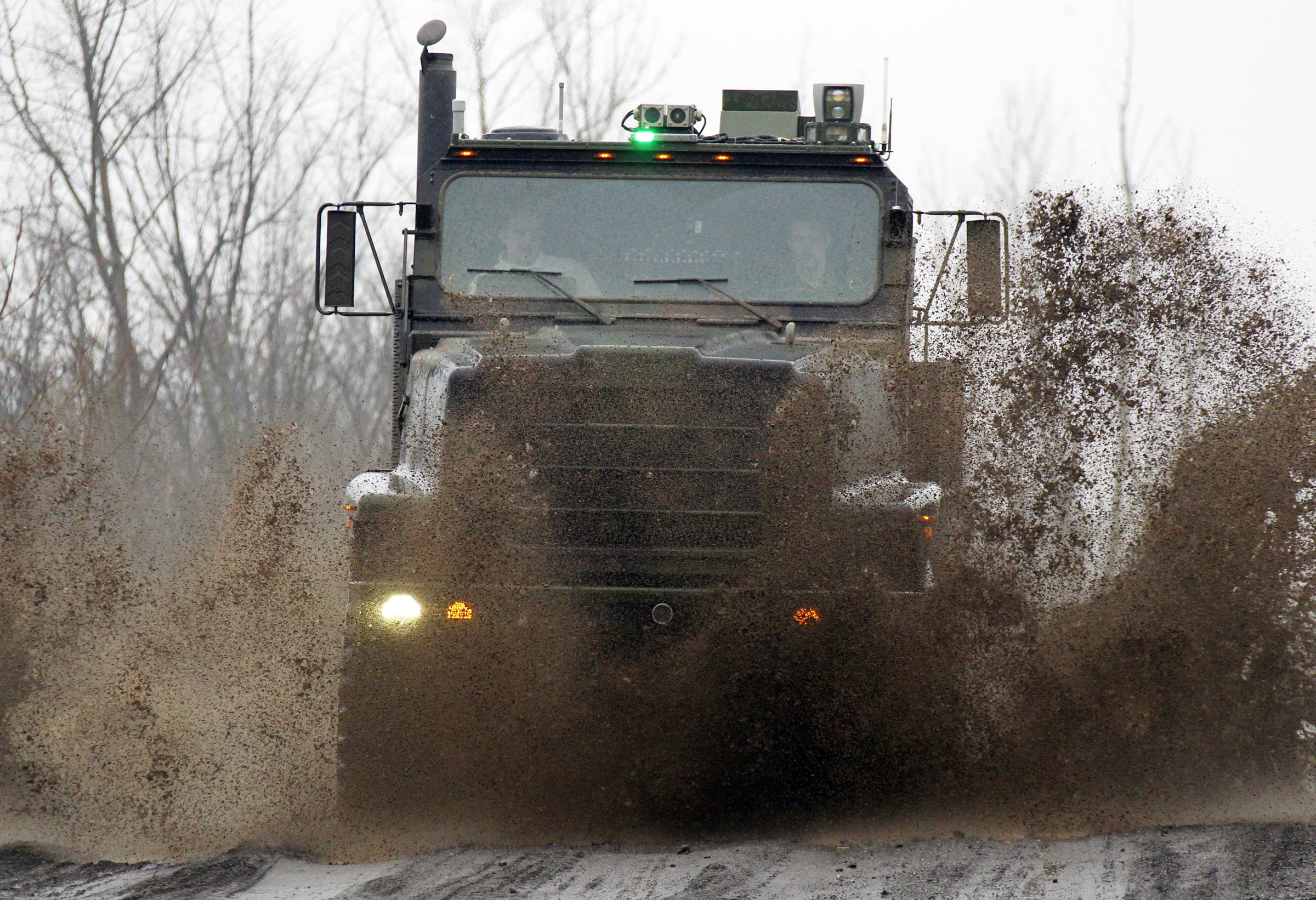 An Oshkosh truck using the TerraMax autonomous driving system drives along a mud-soaked test course outside of Pittsburgh
