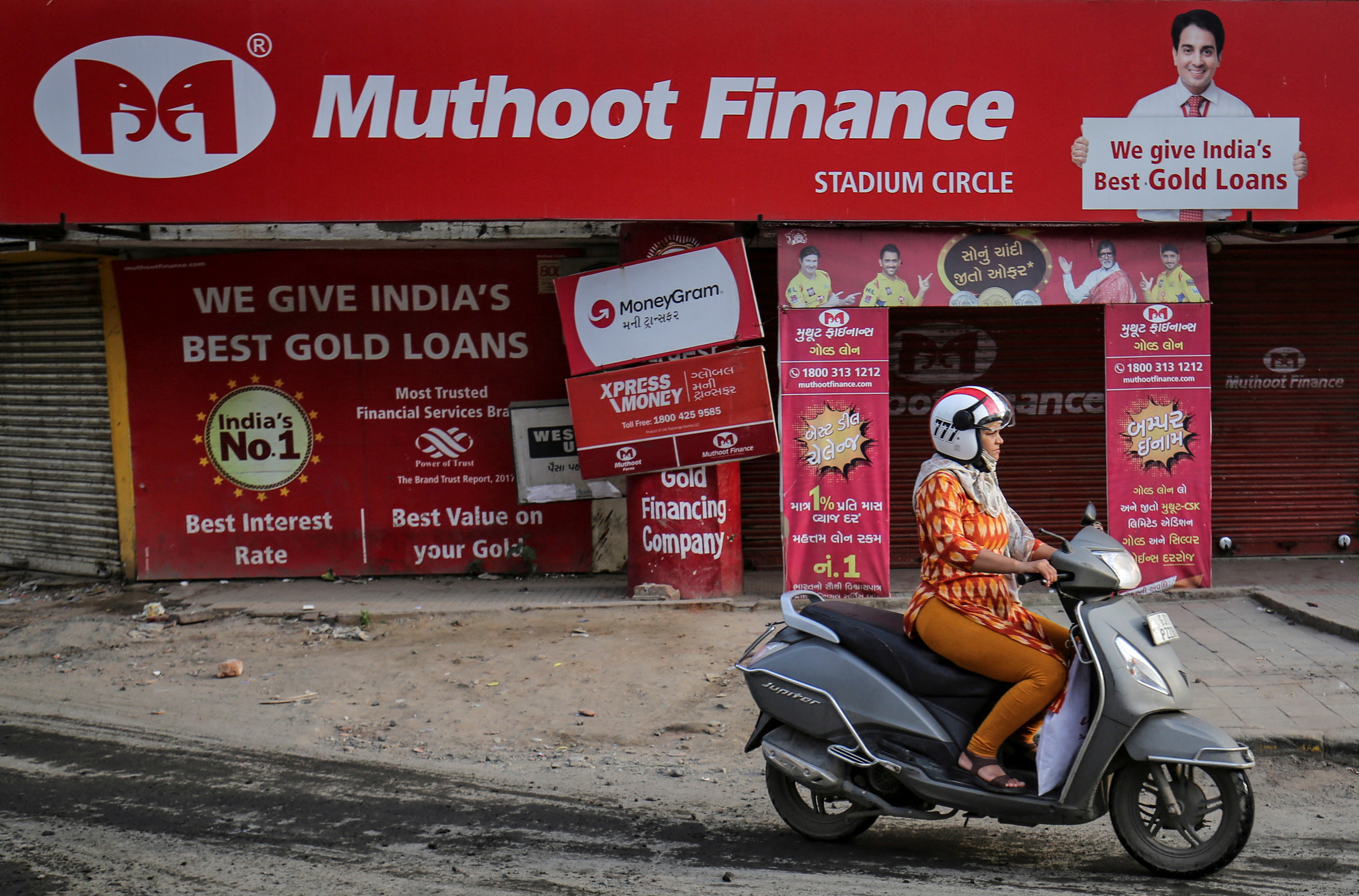 A woman rides her scooter past a Muthoot Finance branch in Ahmedabad