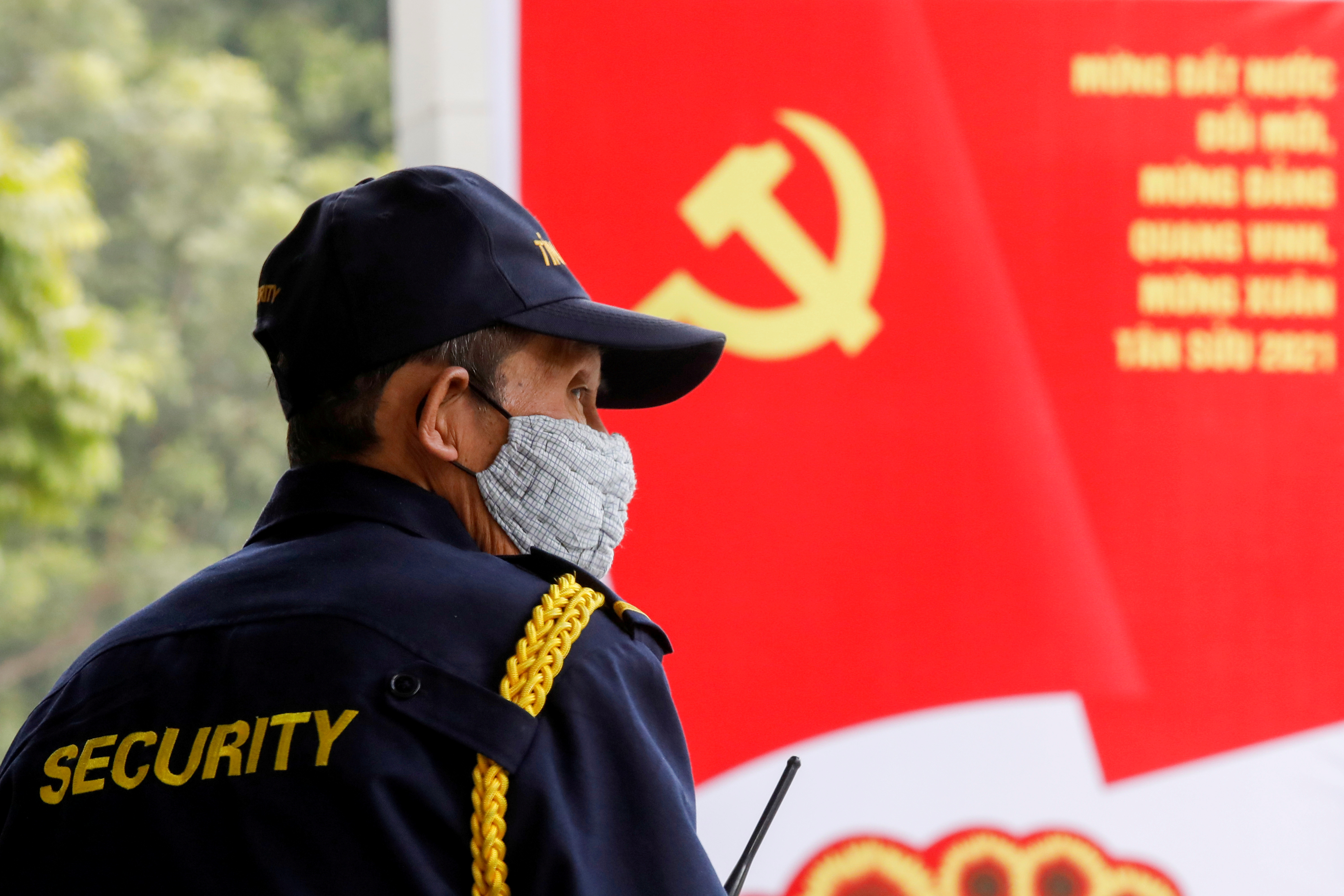 FILE PHOTO: A security officer stands guard near a poster for the upcoming 13th National Congress of the ruling Communist Party of Vietnam