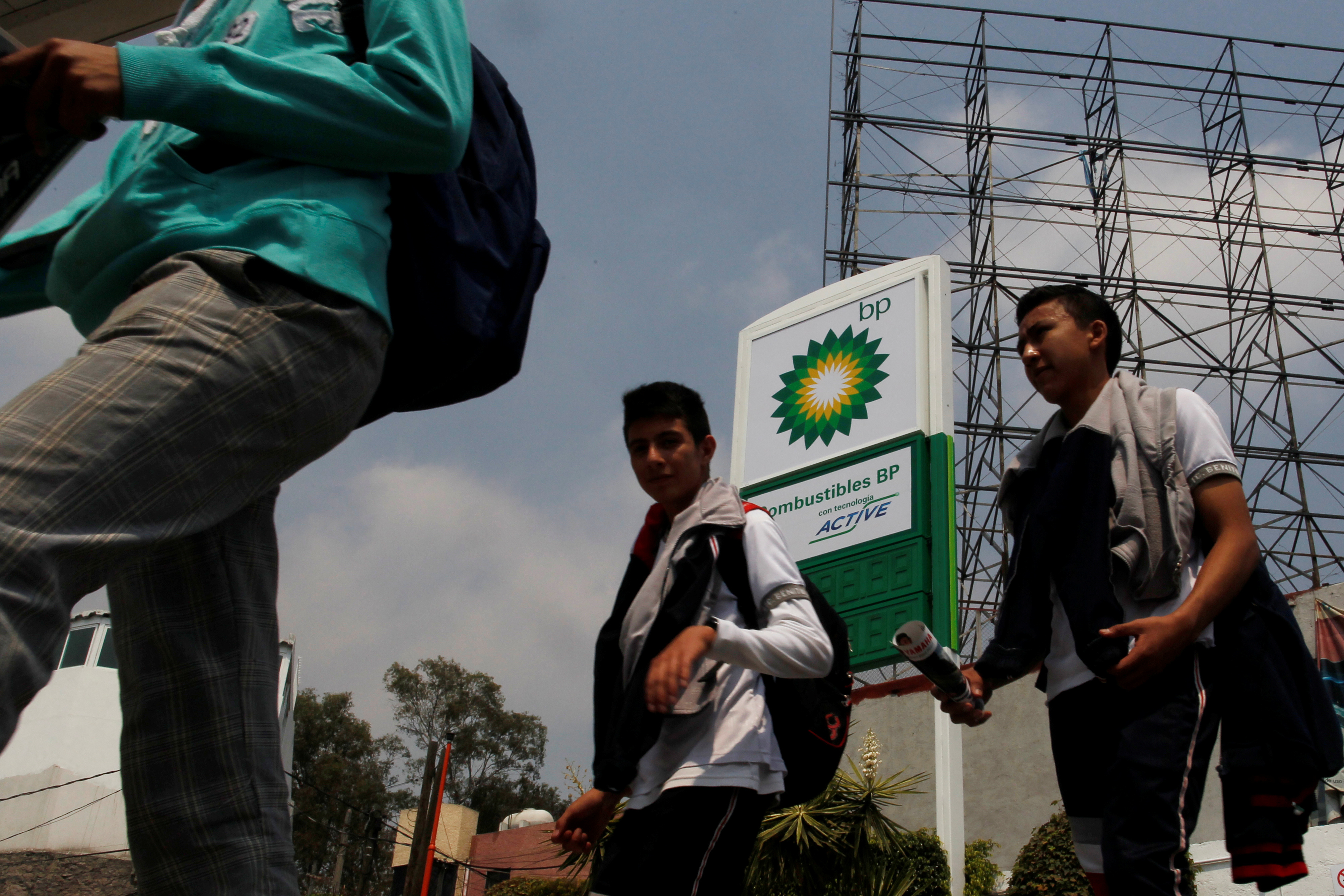 People walk pass a BP logo at the new BP petrol station on the outskirts of Mexico City, Mexico