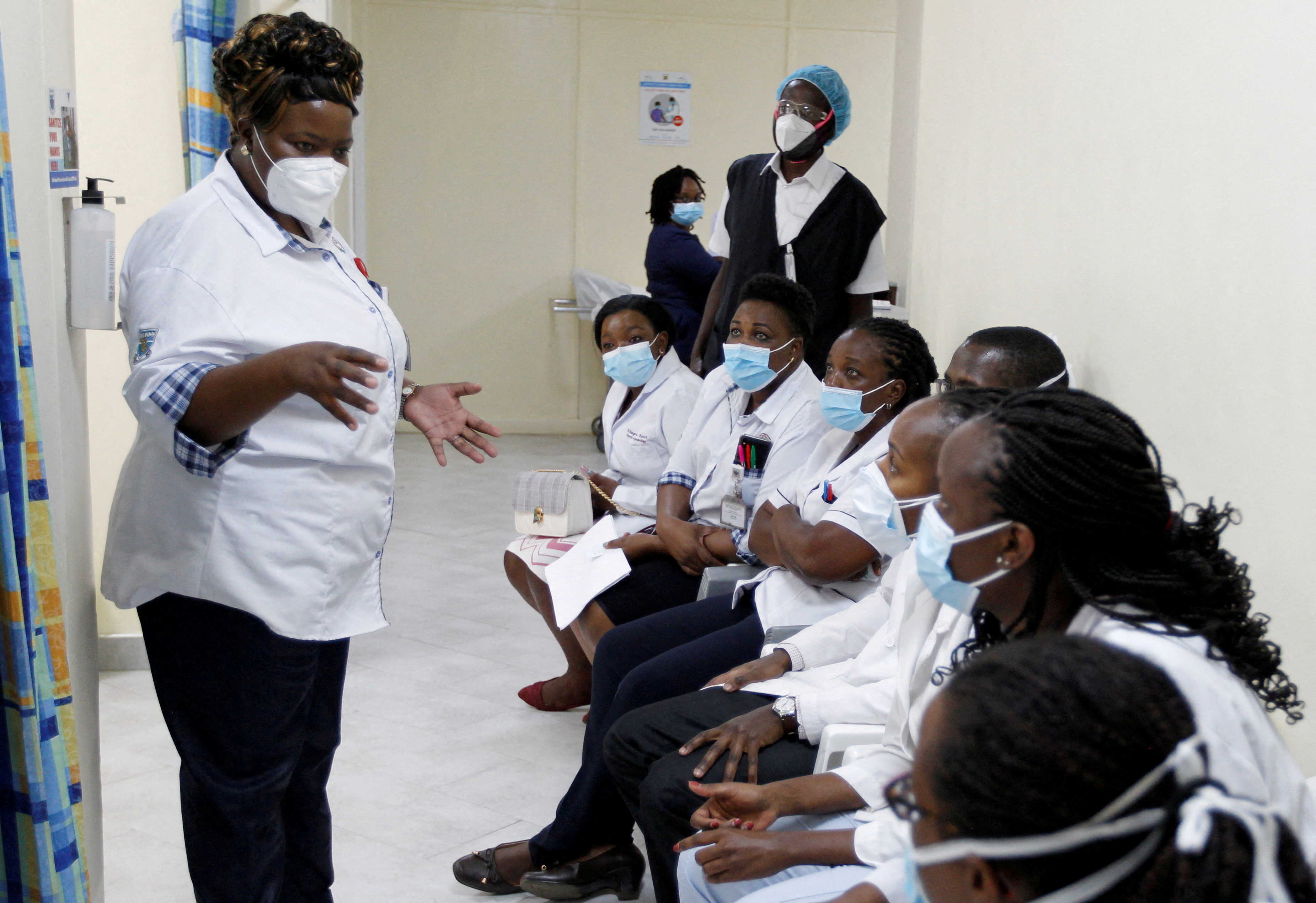A health worker talks to her colleagues as they prepare to receive the AstraZeneca/Oxford vaccine under the COVAX scheme against coronavirus disease (COVID-19) at the Kenyatta National Hospital in Nairobi,