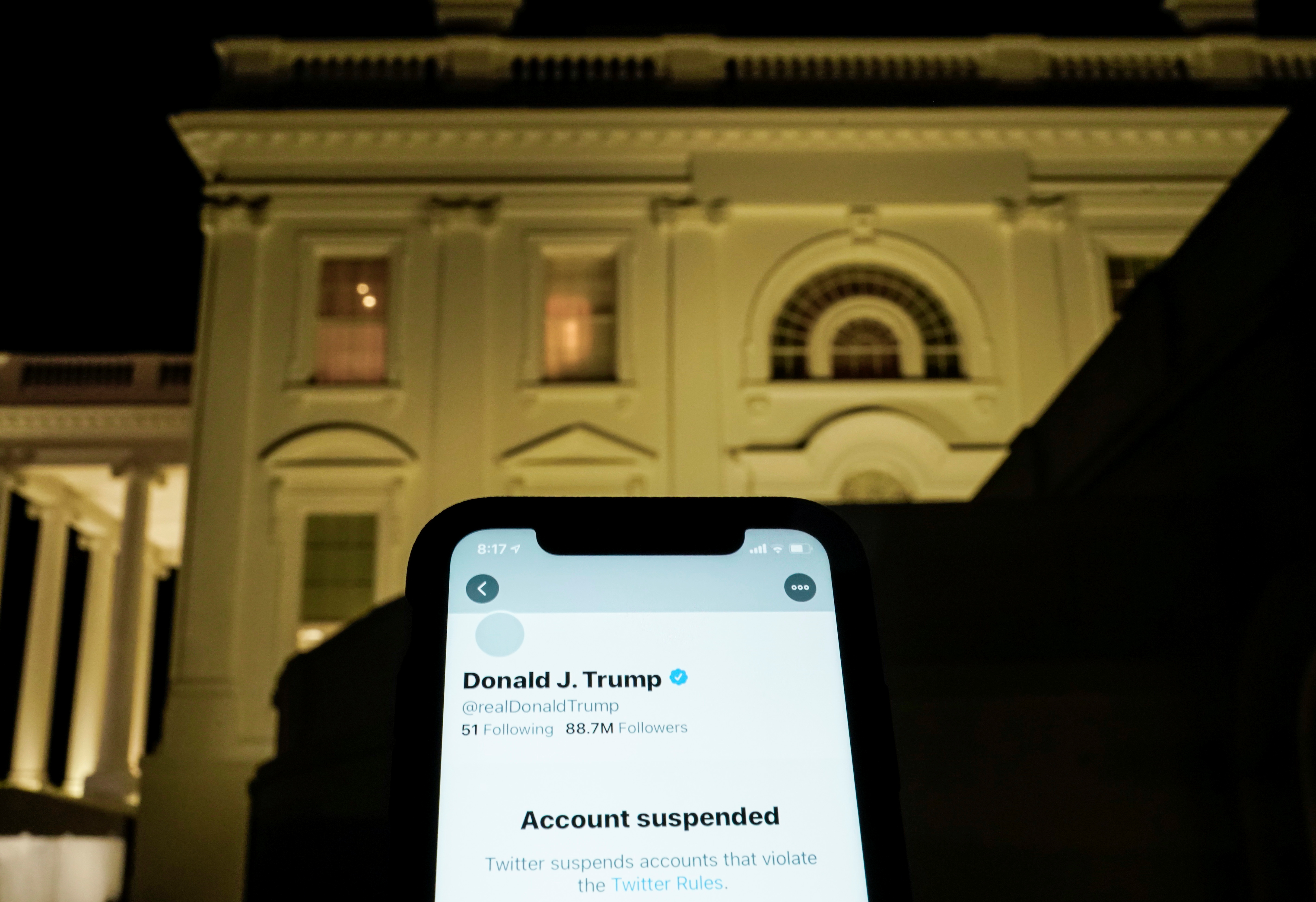 A photo illustration shows the suspended Twitter account of U.S. President Donald Trump on a smartphone and the White House in Washington