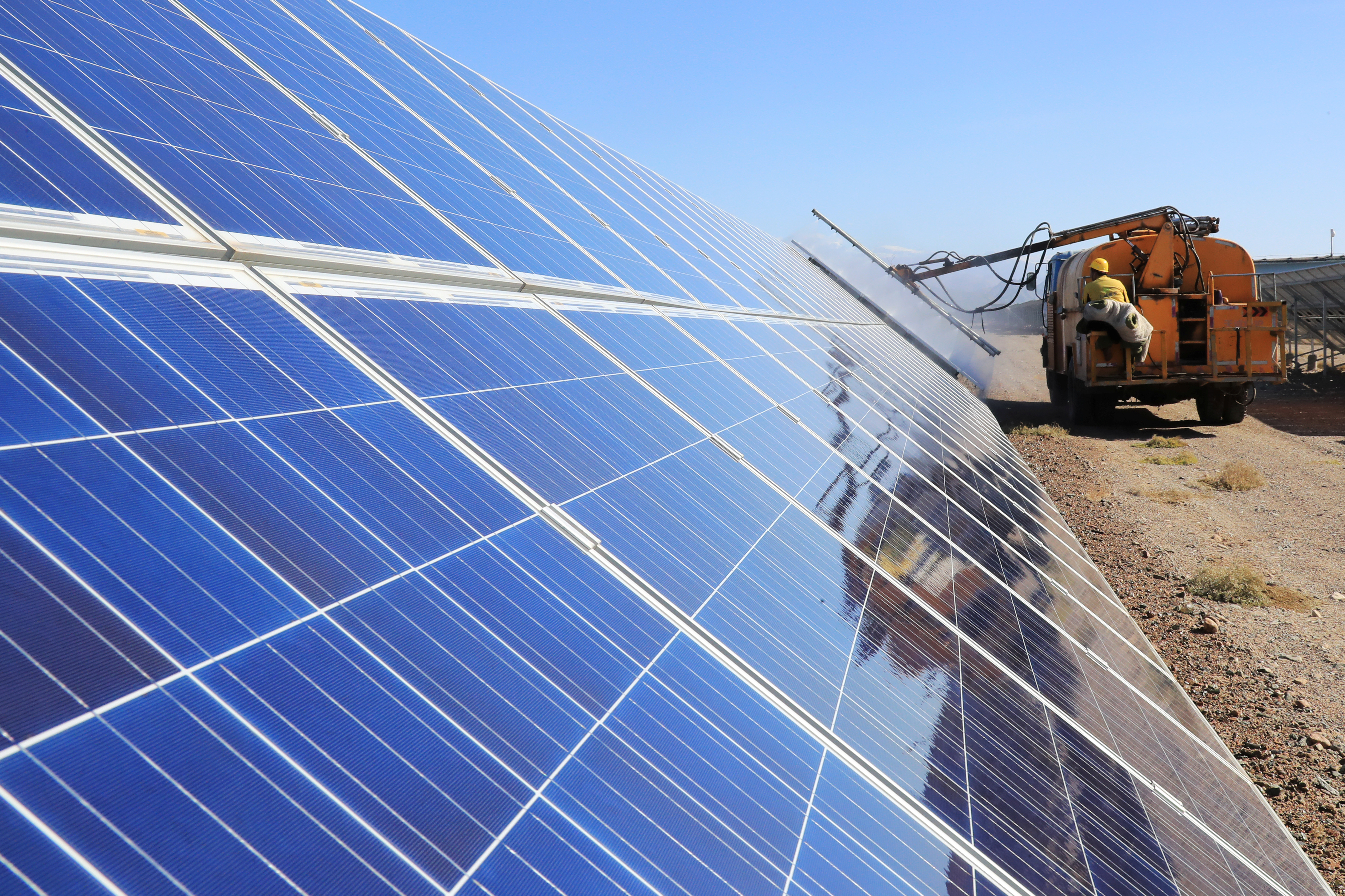 Worker operates a machinery to clean solar panels at a photovoltaic industrial park in Hami