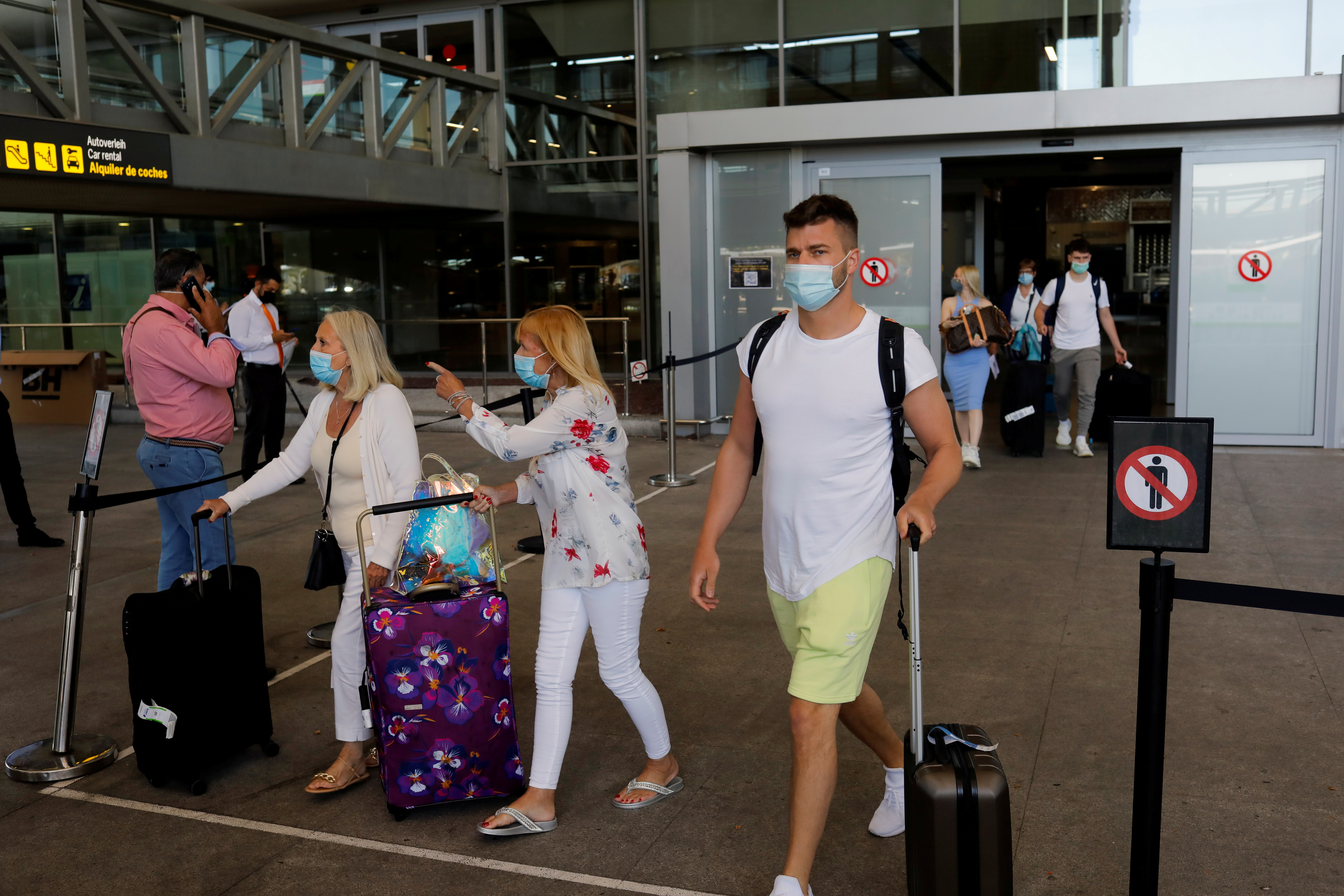 Tourists wearing protective face masks walk with their luggage as they arrive at Malaga-Costa del Sol Airport, in Malaga, Spain, June 7, 2021.