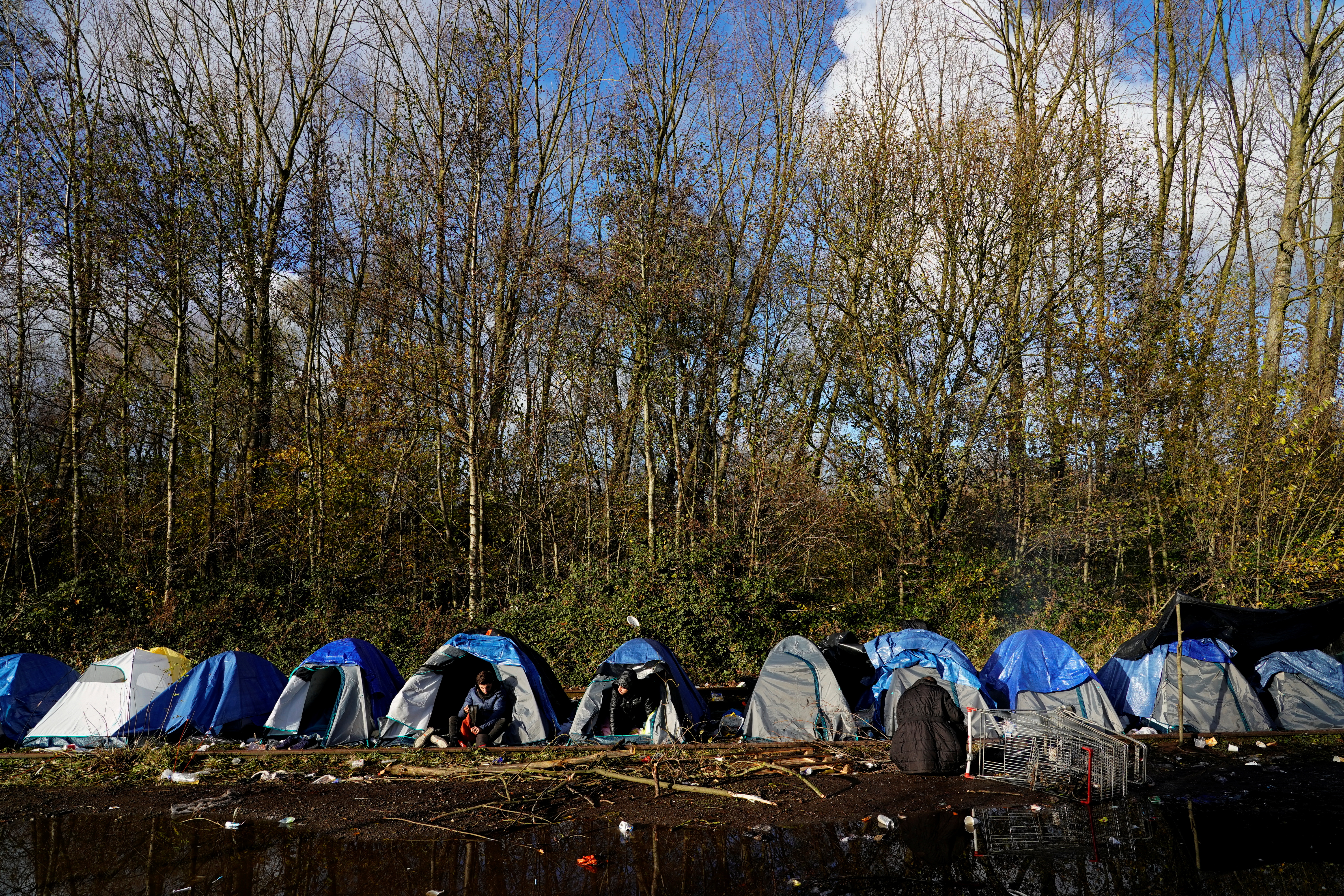 Kurdish migrants sit at a makeshift camp in Loon-Plage near Dunkirk, France, November 29, 2021. REUTERS/Juan Medina