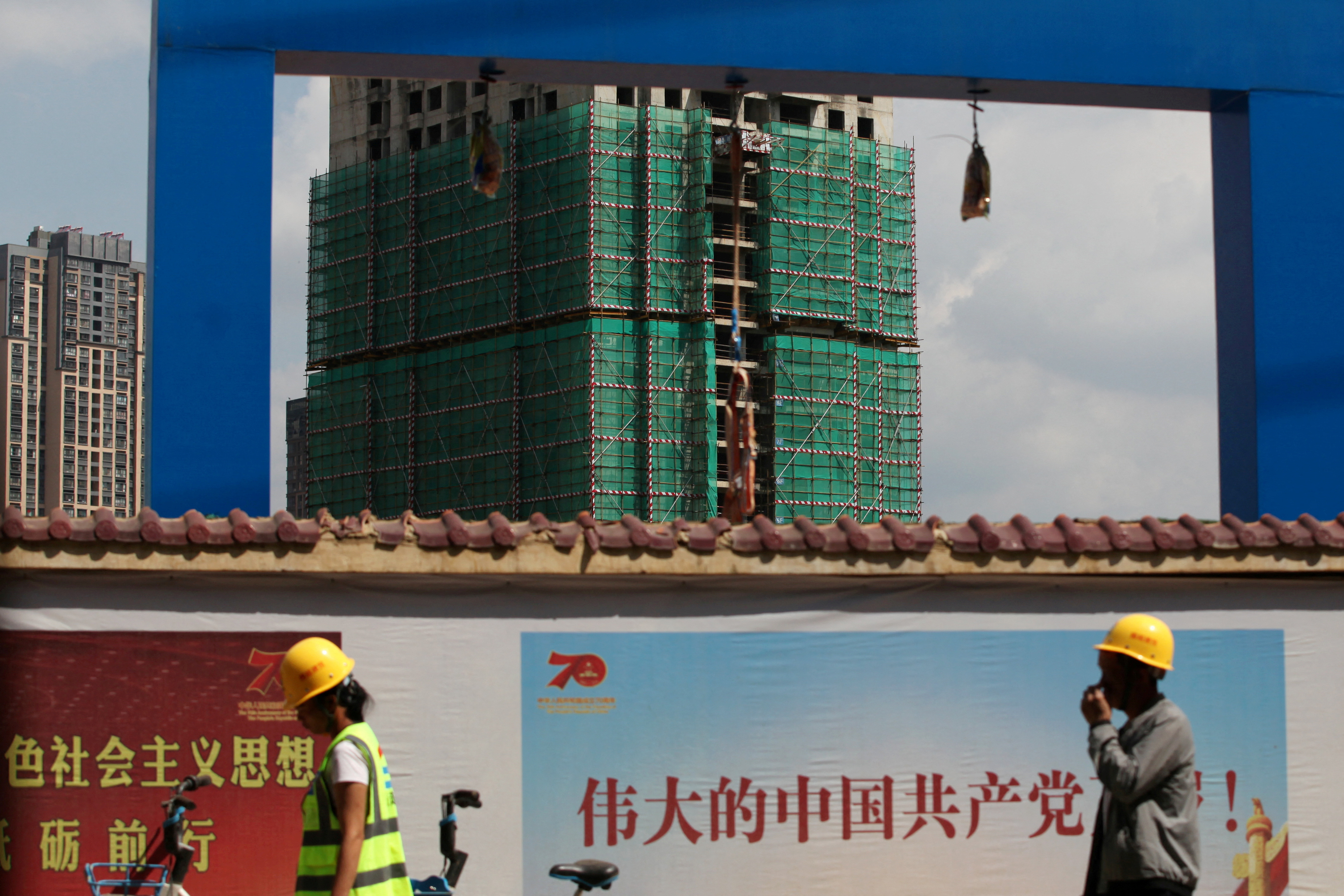 Workers walk past a construction site of residential buildings by property developer Country Garden in Kunming, Yunnan