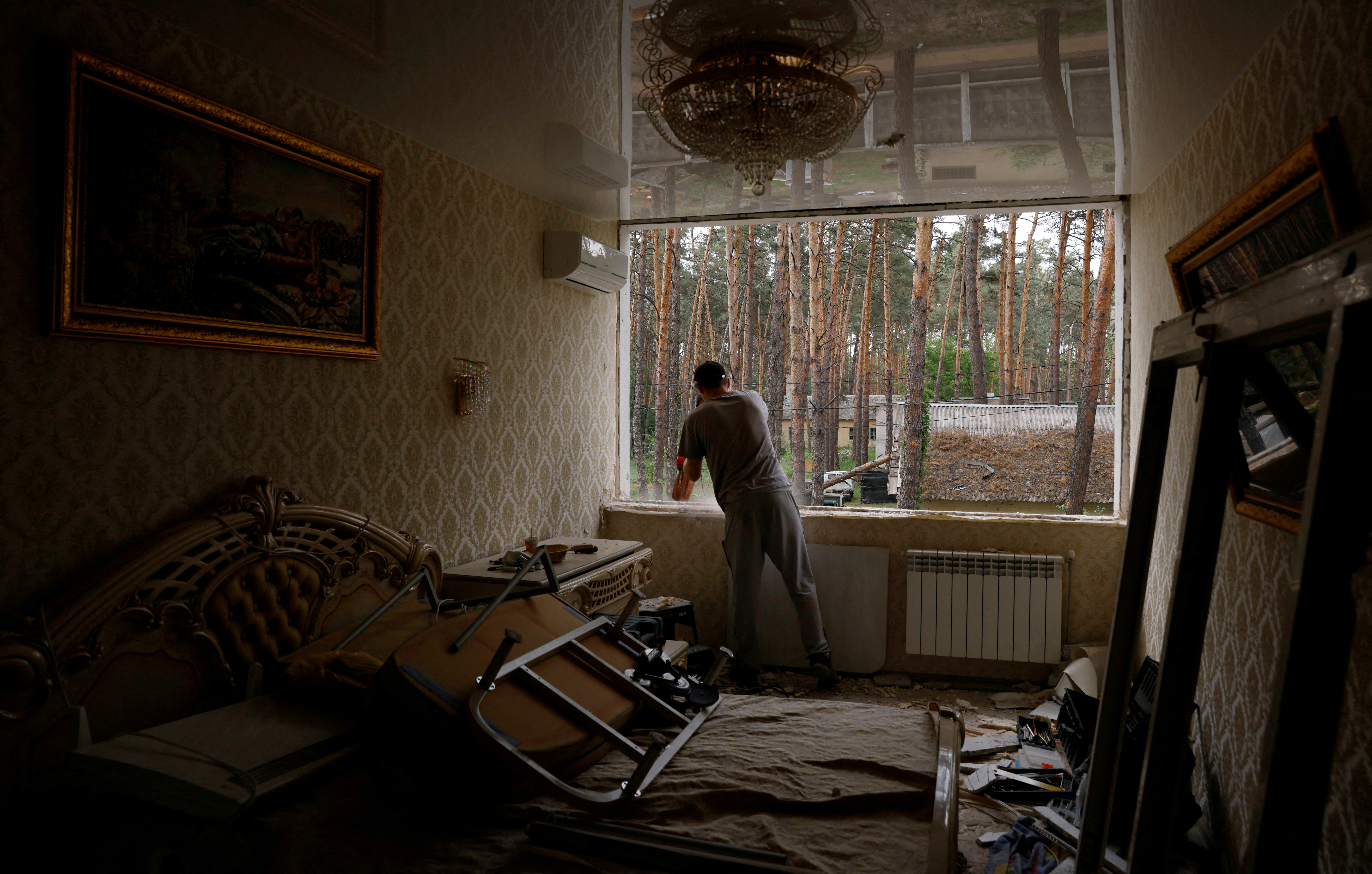 Oleg Khodyrev, 29, installs new windows in an apartment destroyed by Russia's attacks on Irpin, outside Kyiv