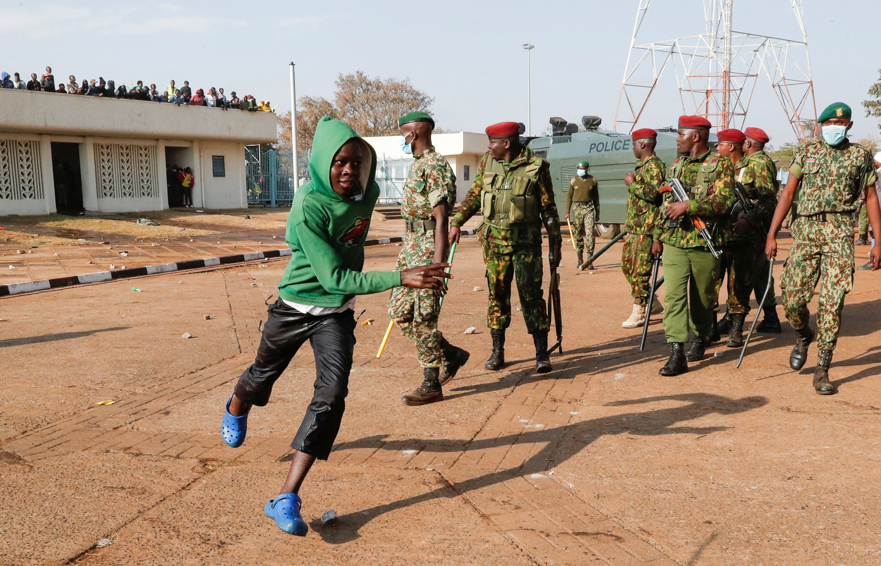 A boy runs past riot police as they attempt to control people jostling to attend the inauguration of Kenya's President William Ruto before his swearing-in ceremony at the Moi International Stadium Kasarani, in Nairobi