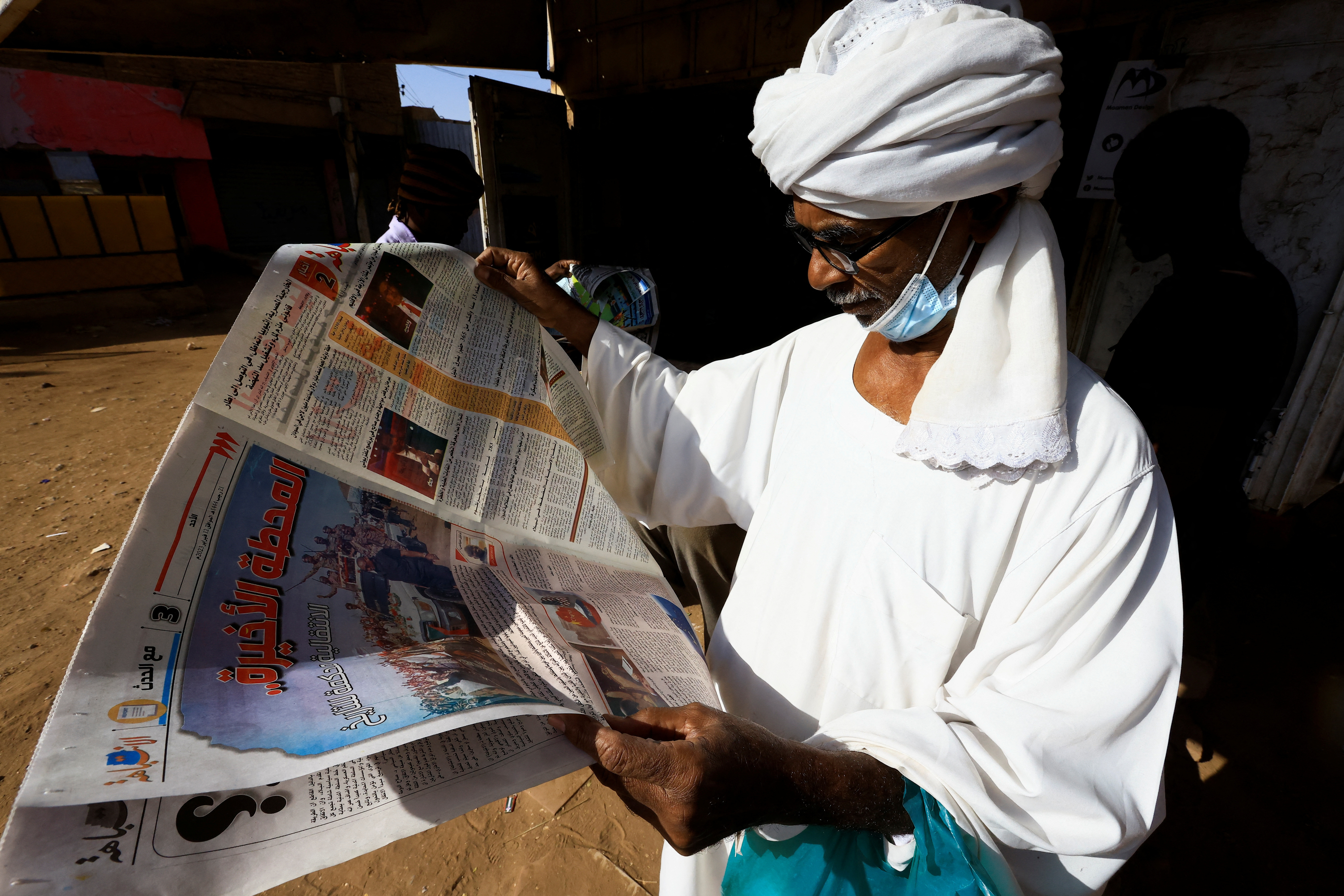 A man reads a newspaper near the Al-Zikriyat library in Omdurma
