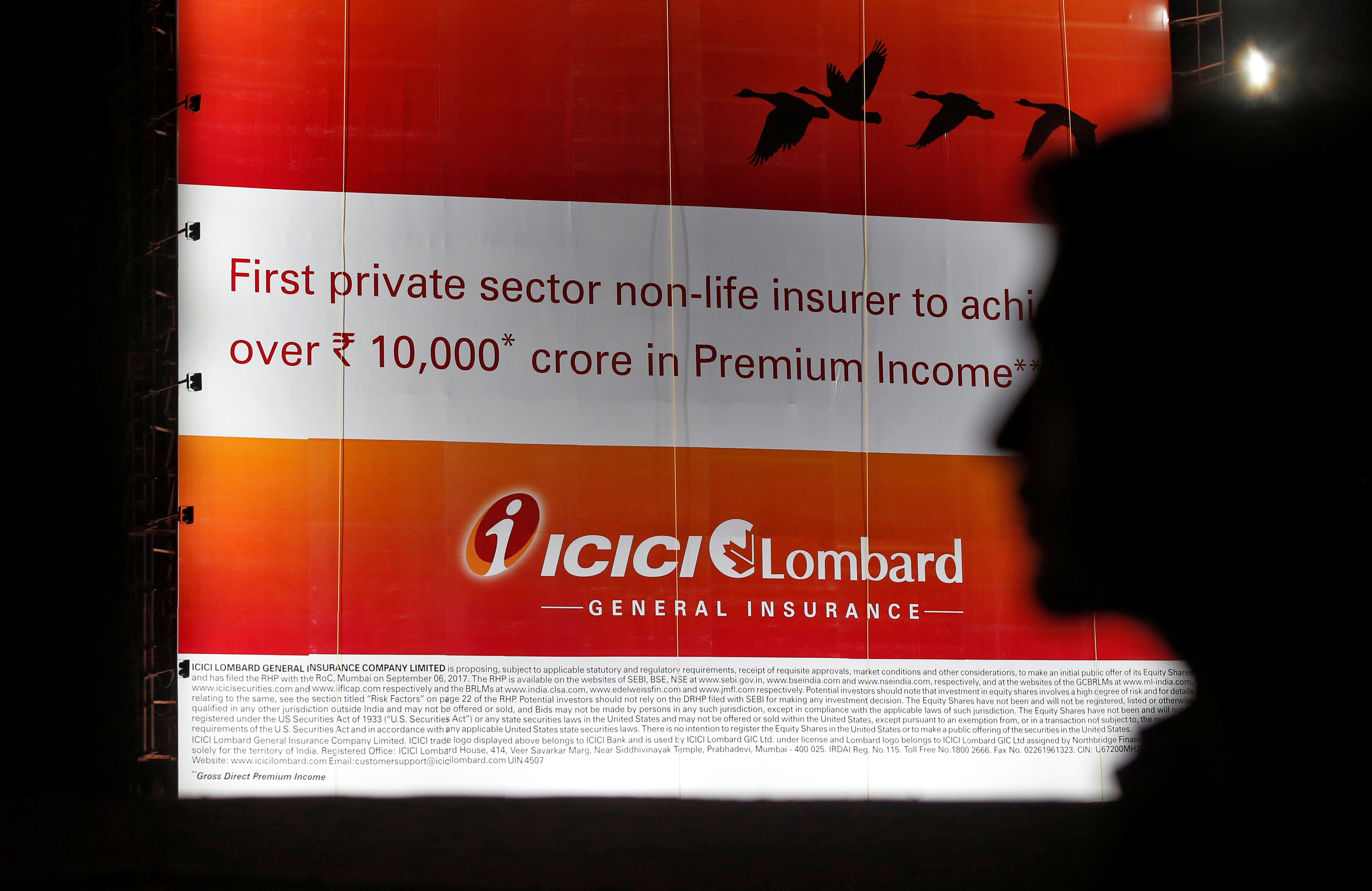 A man walks past a billboard of Indian insurer ICICI Lombard in Mumbai