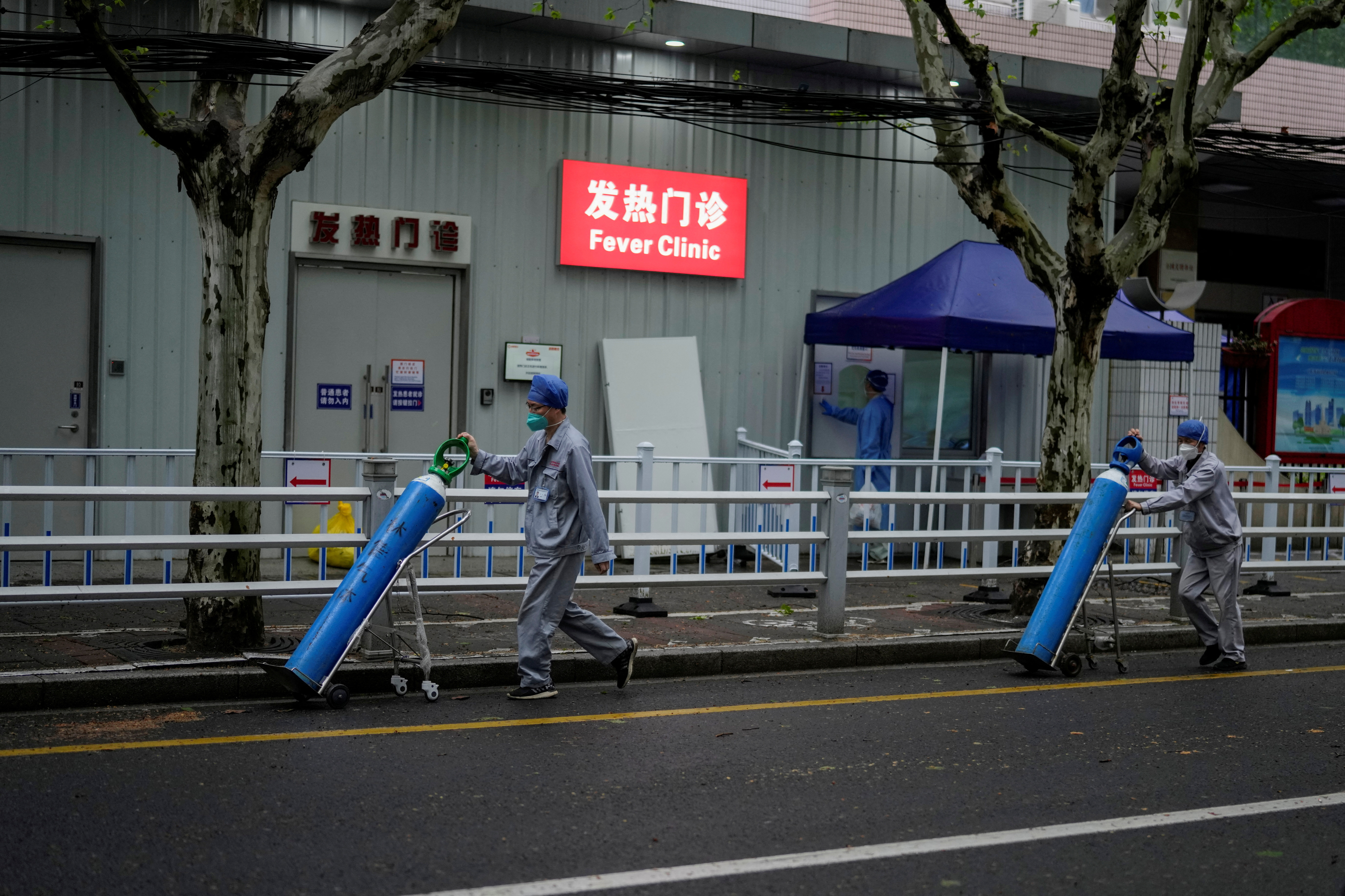 Workers deliver oxygen cylinders outside a hospital in Shanghai