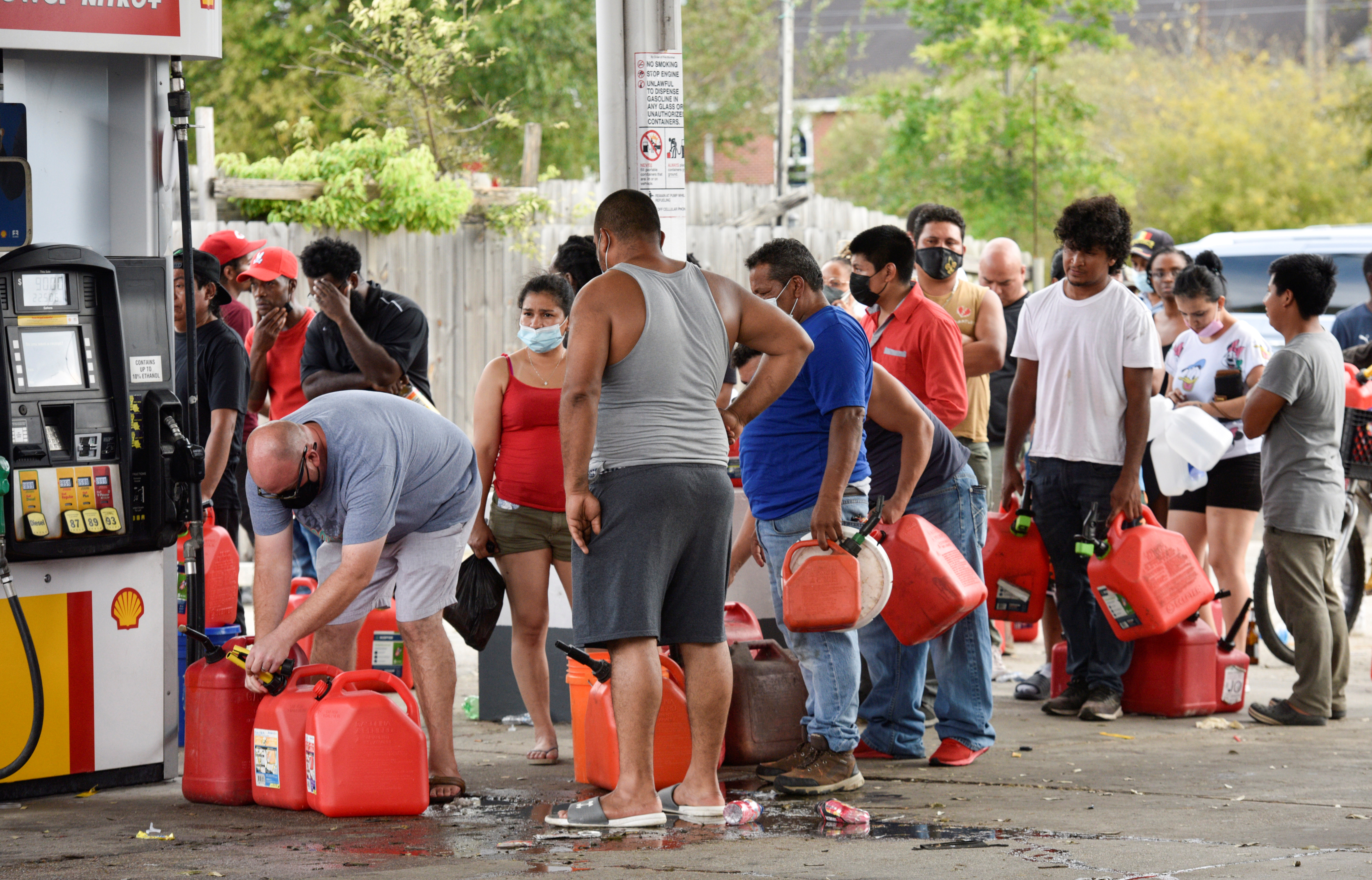 Three days after Hurricane Ida knocked out power throughout the city, residents wait in long lines at a neighborhood gas station to fill fuel containers for cash only sales in New Orleans