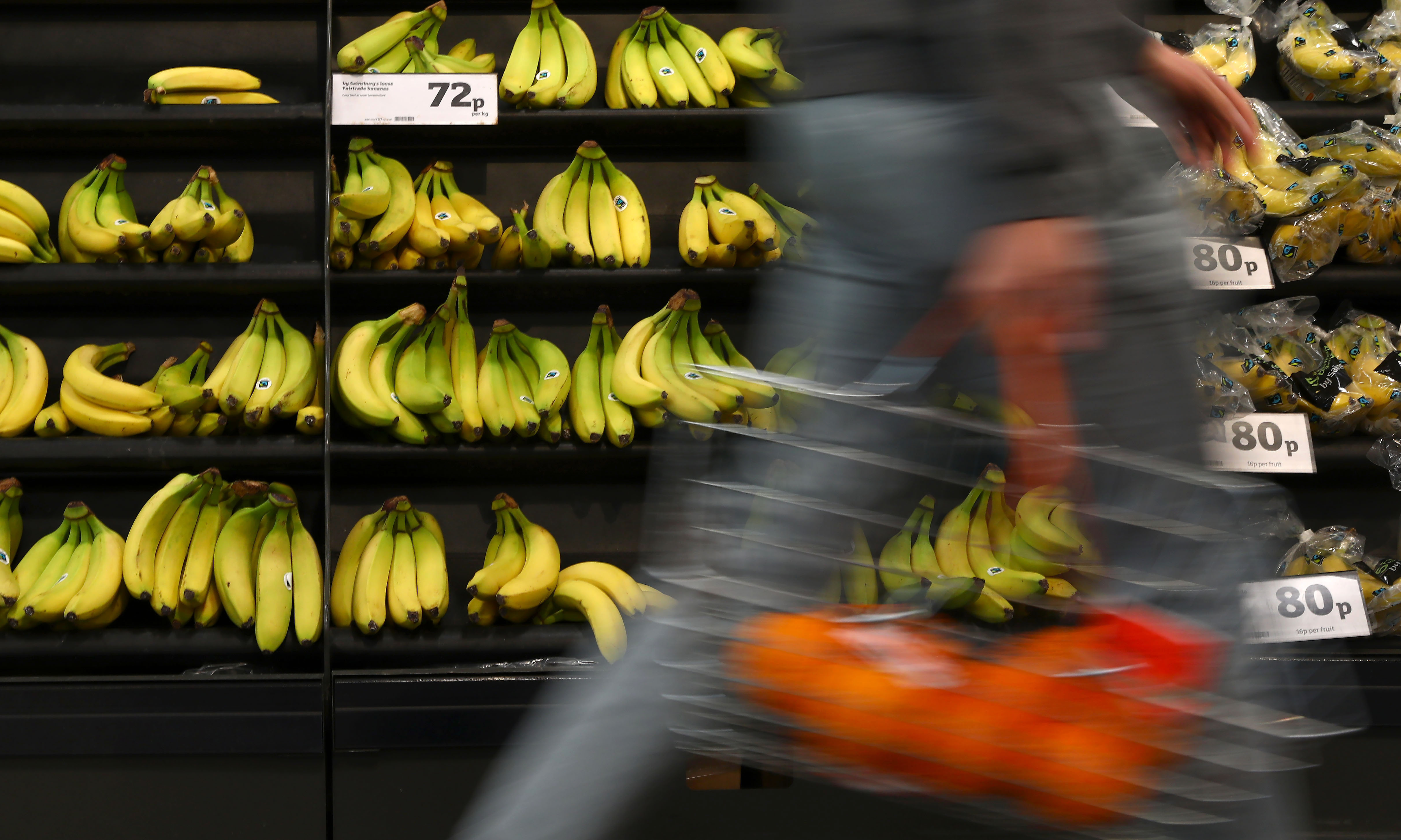 A shopper passes a display of bananas a supermarket in London