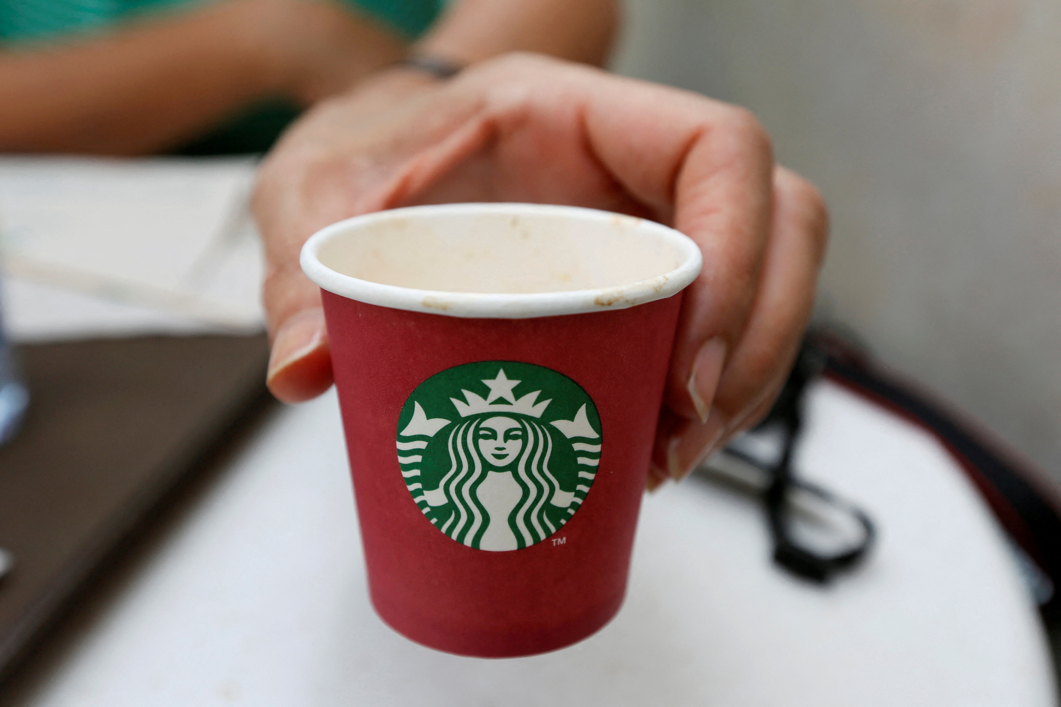 A woman displays a red Starbucks cup at a Starbucks cafe in Beirut
