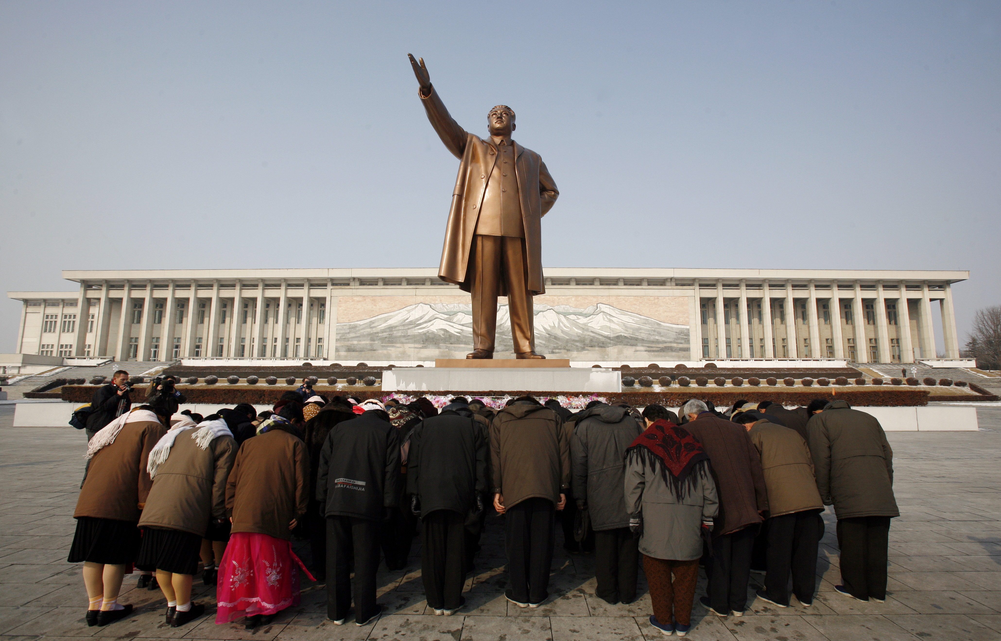 A group of people bow at the base of the giant bronze statue of the state founder and 'Great Leader' Kim-Il Sung in the North Korean capital of Pyongyang February 26, 2008.       REUTERS/David Gray/Files
