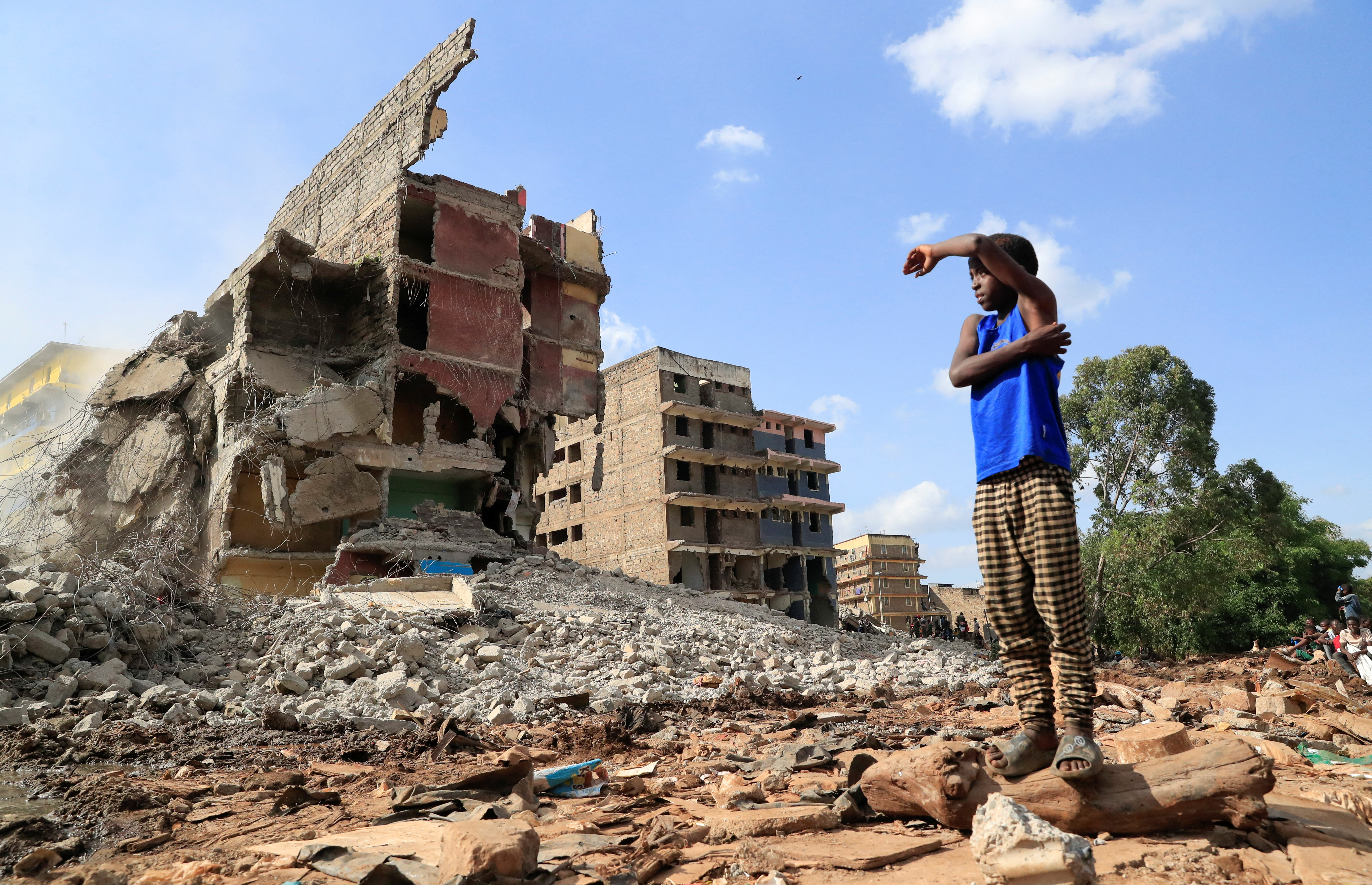 A boy looks at the search and rescue operations on the rubble of a residential flat built on riparian land, that collapsed while undergoing demolition in Nairobi