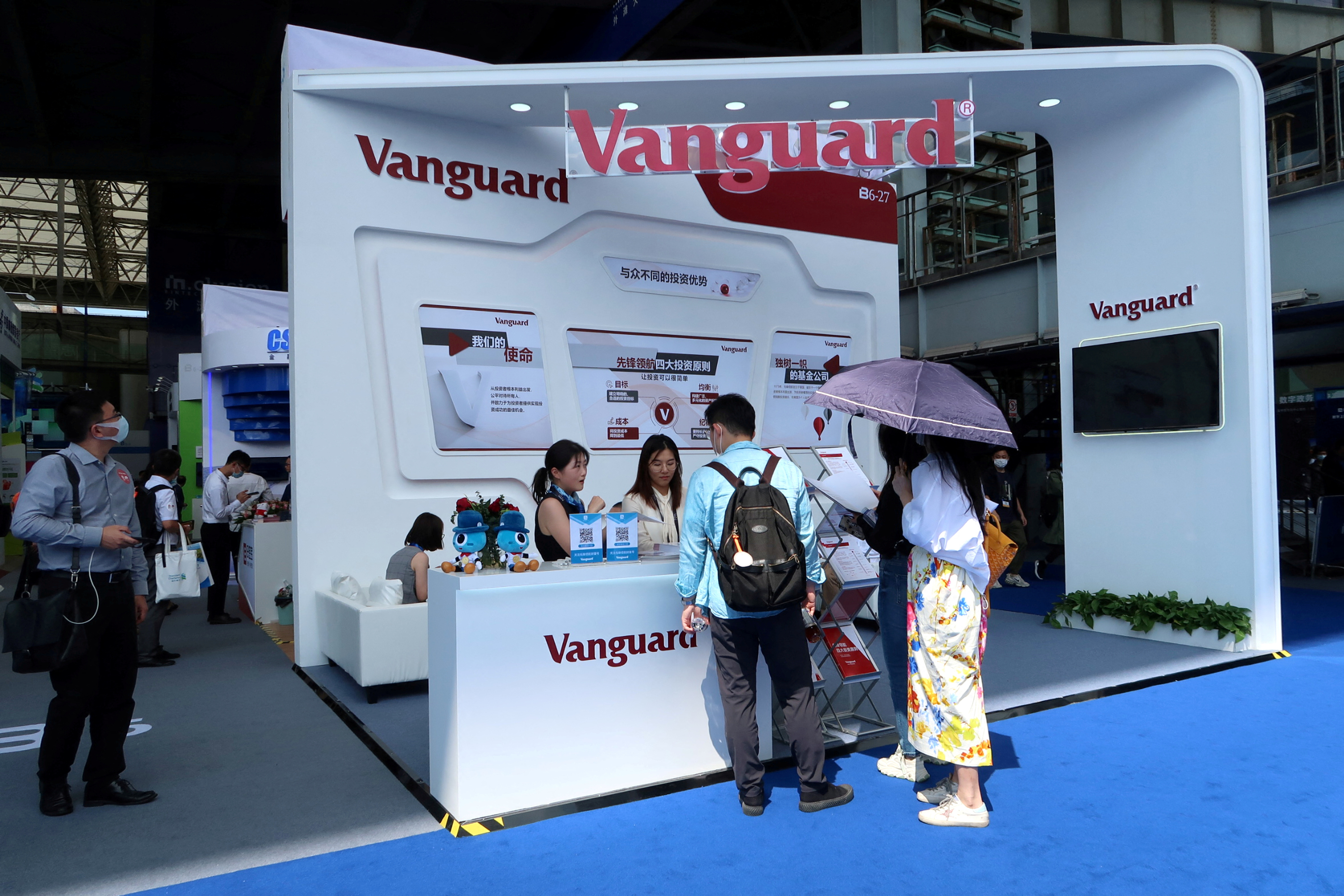 People are seen at a booth of Vanguard Group at a fair during the INCLUSION fintech conference in Shanghai