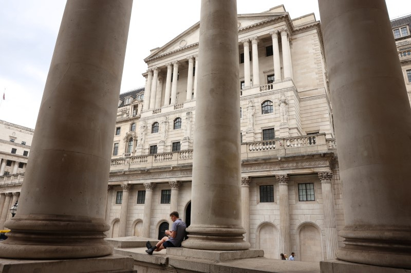 A man sits by the Bank of England in the financial district of London