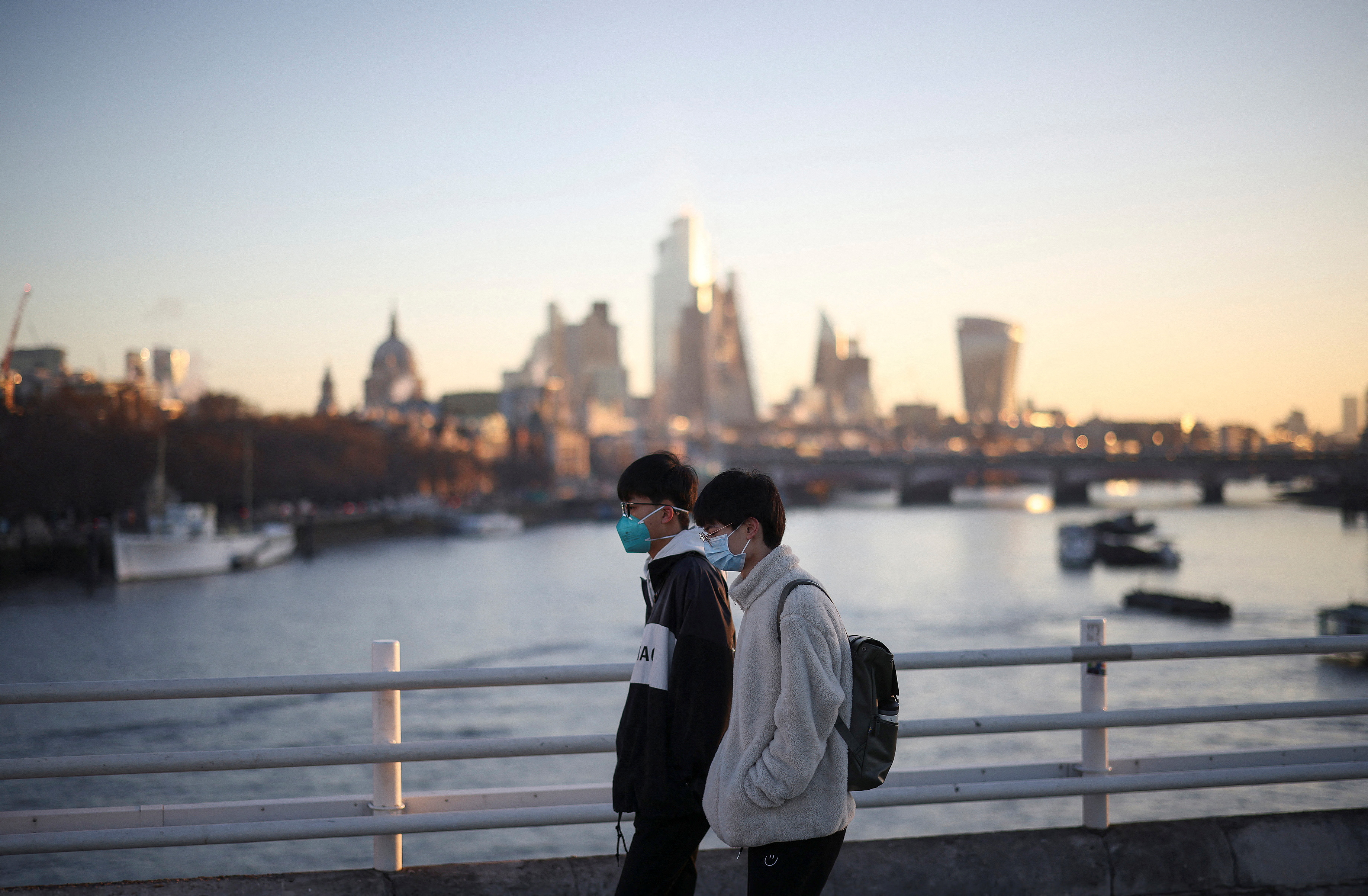 People wearing protective face masks walk over Waterloo Bridge during morning rush hour, amid the ongoing coronavirus disease (COVID-19) pandemic in London