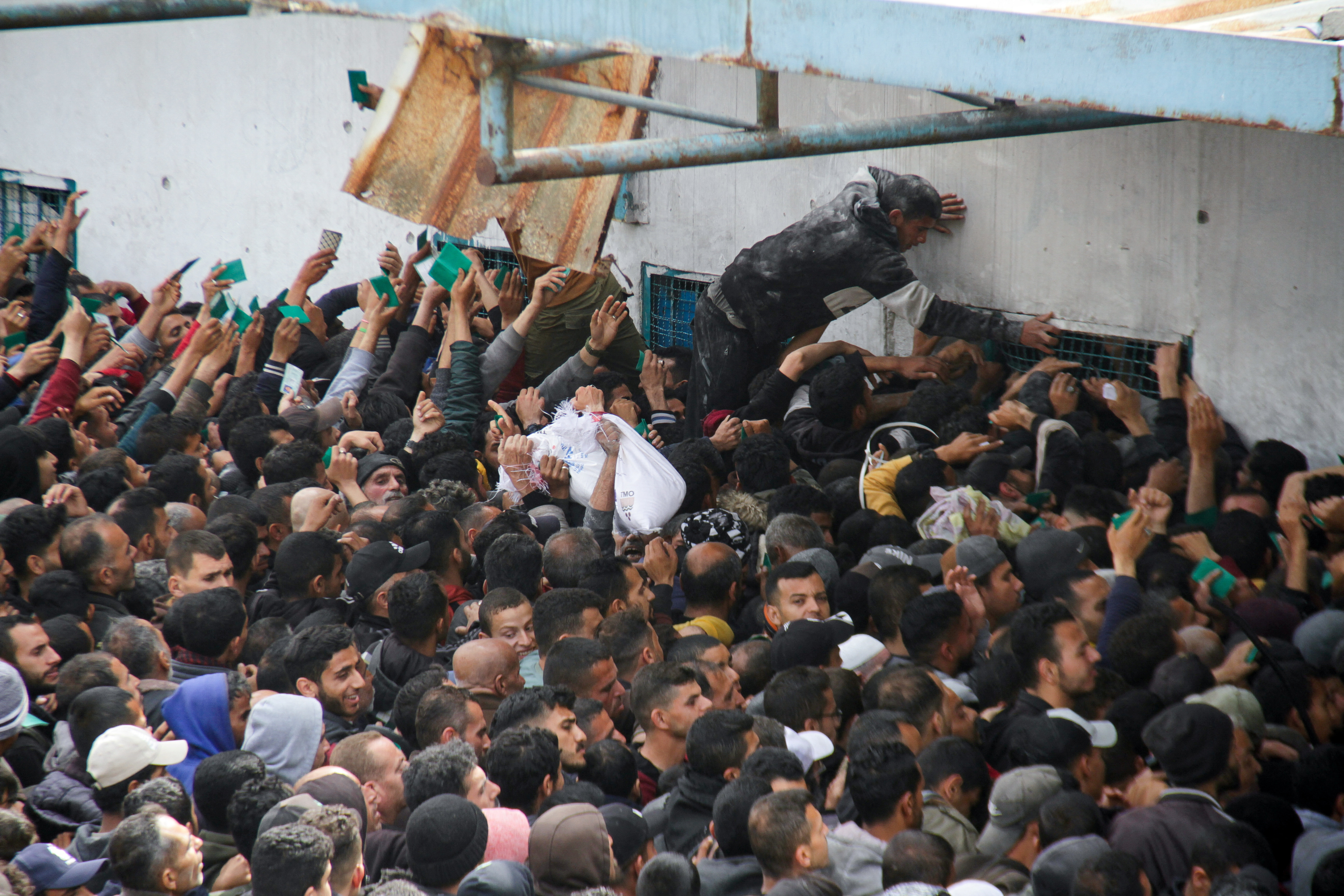 Palestinians gather to receive aid outside an UNRWA warehouse in Gaza City