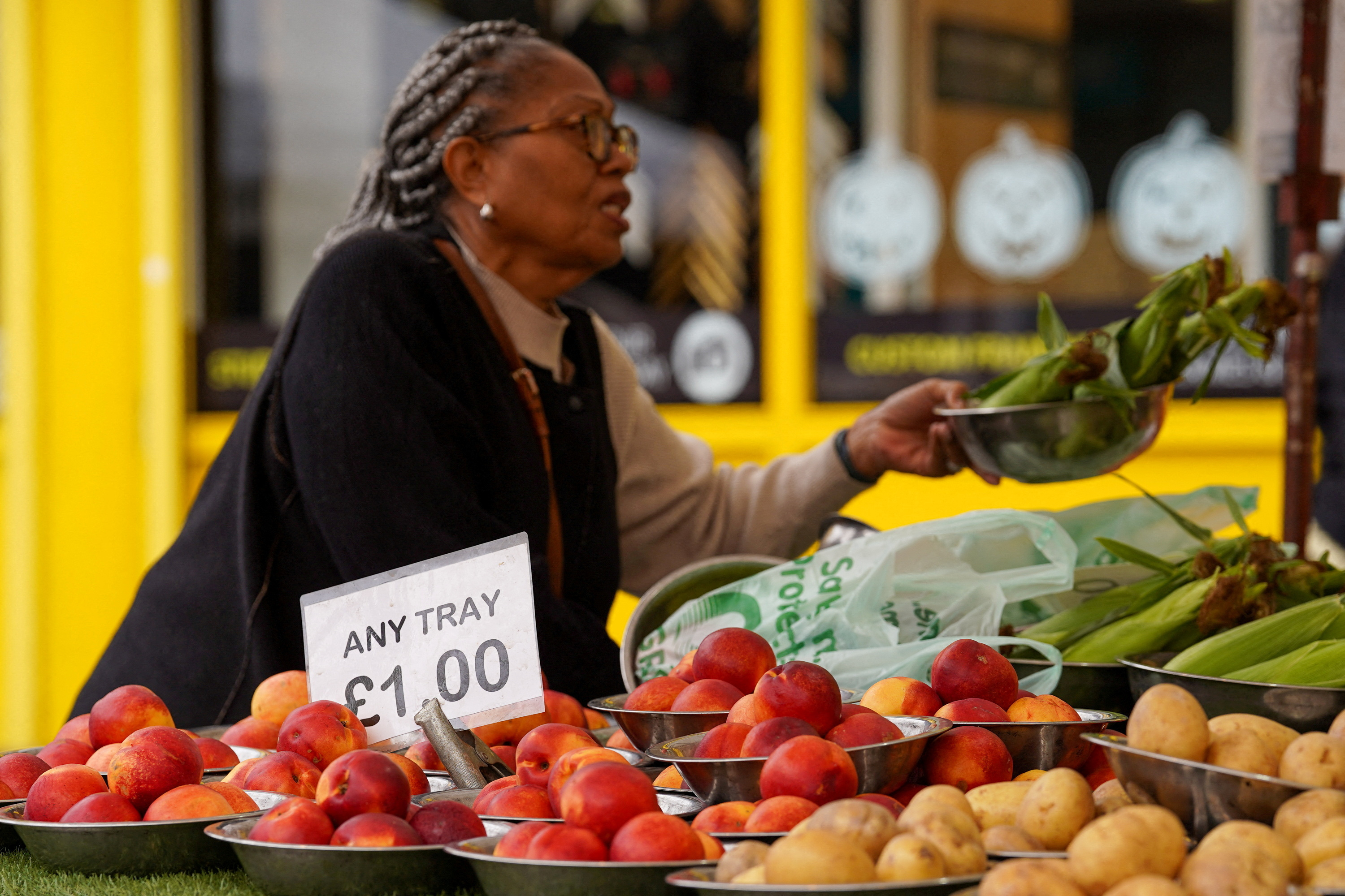 A woman shops for food items at a market stall in London
