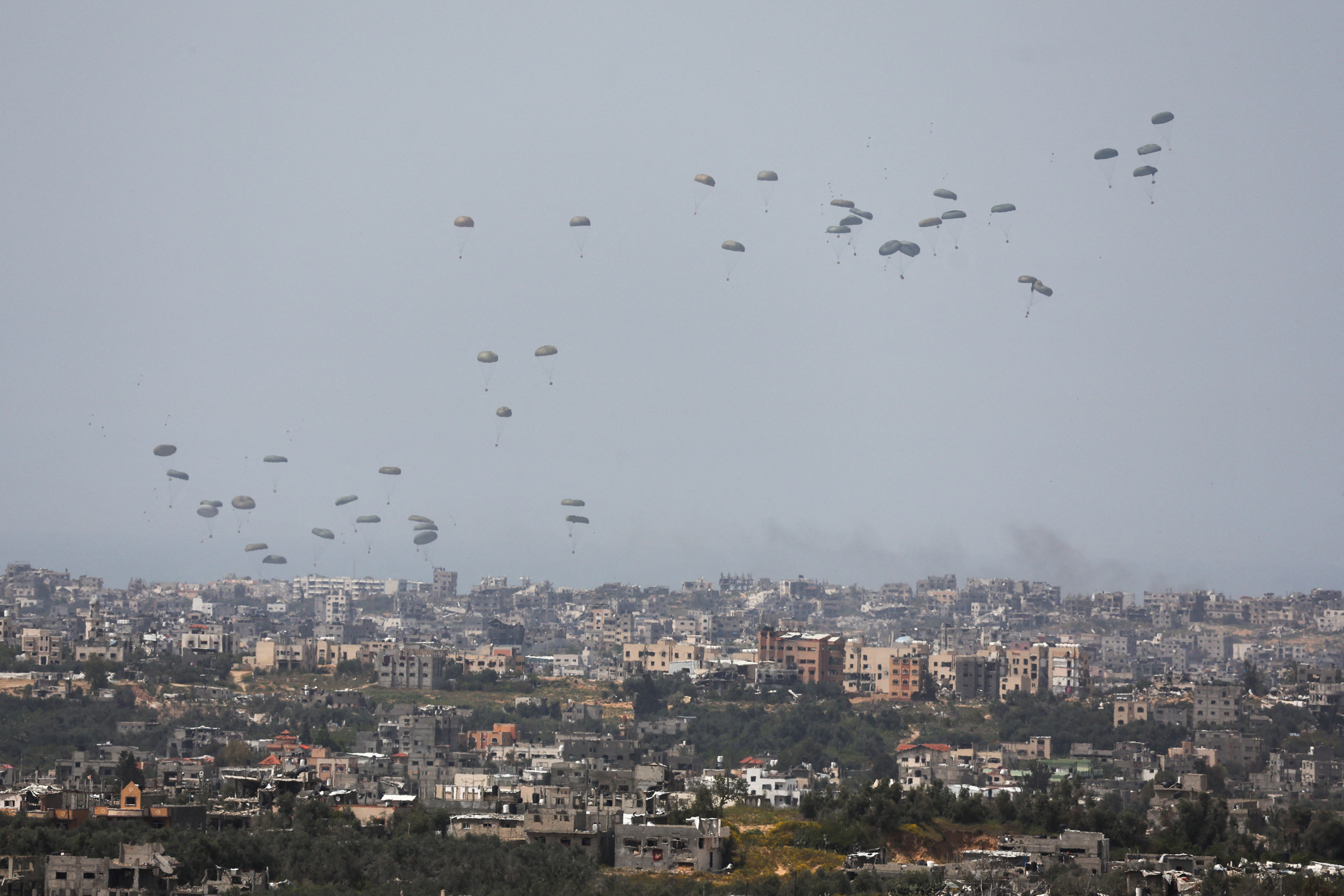 Humanitarian aid falls through the sky towards the Gaza Strip, as seen from Israel