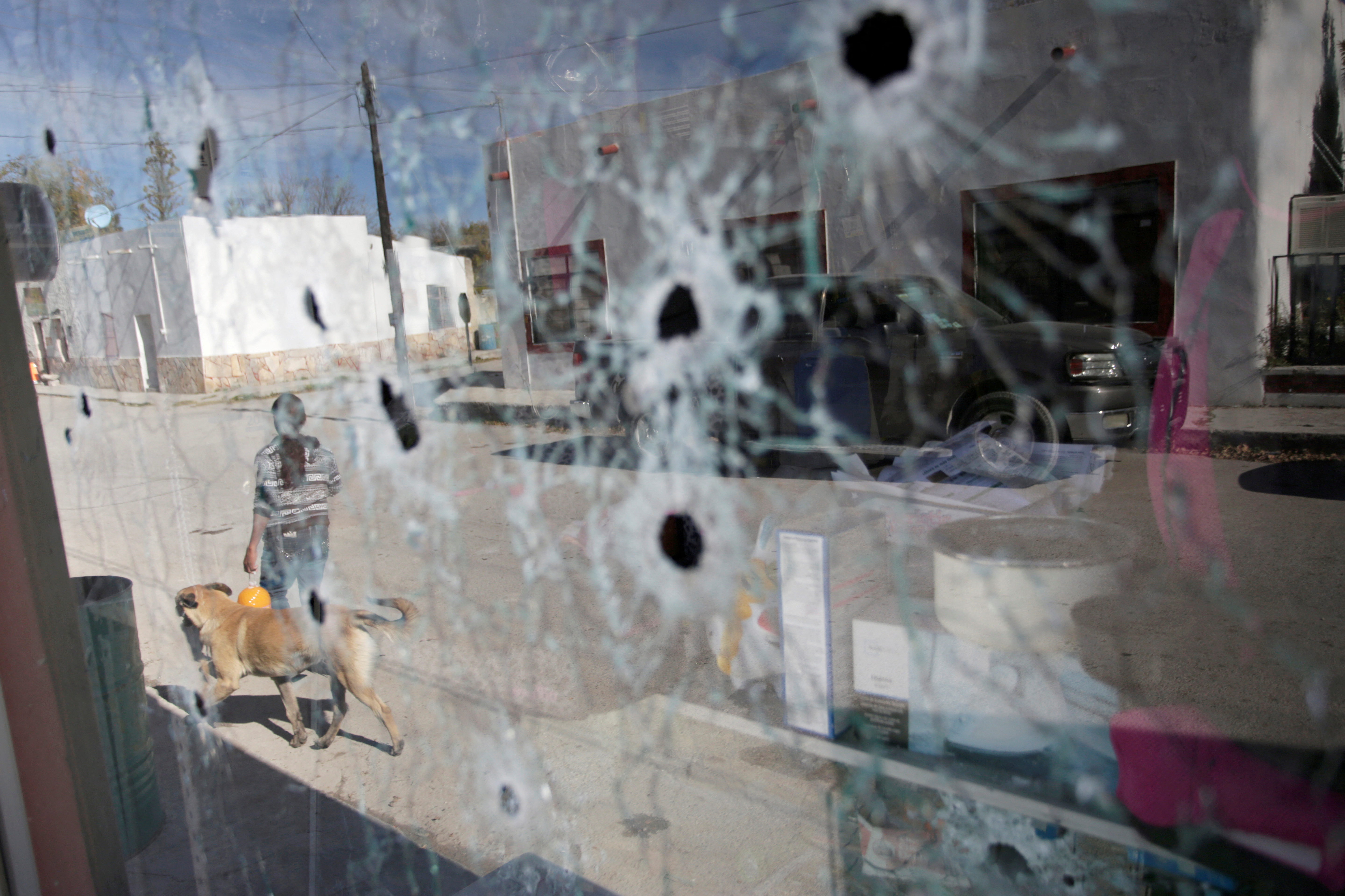 A woman is pictured through a bullet-riddled glass of a store, days after a gun battle between police and hitmen, in the municipality of Villa Union