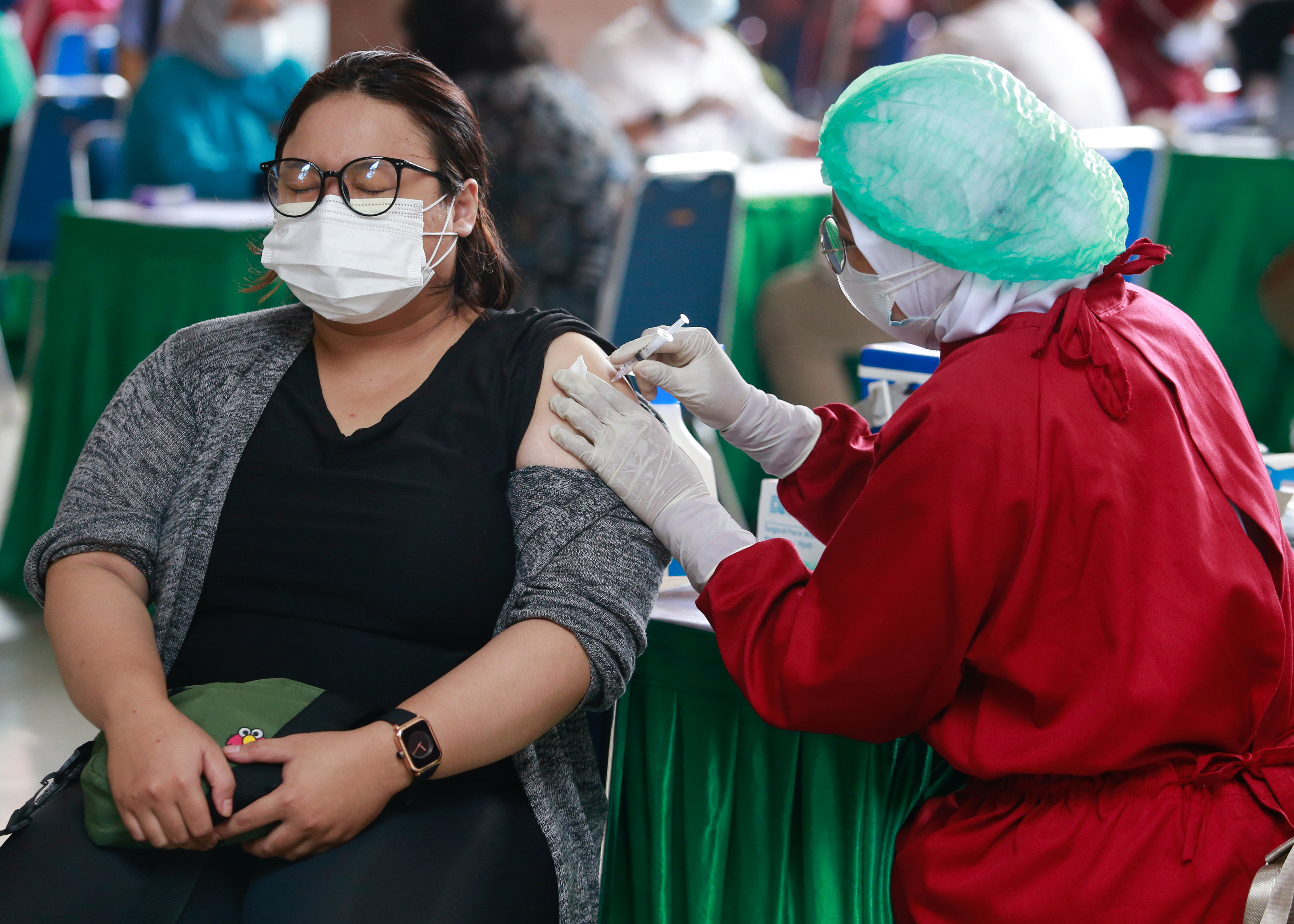 A woman reacts as she receives a dose of the coronavirus disease (COVID-19) vaccine during the mass vaccination program at the Tangerang City Government Center, in Tangerang on the outskirts of Jakarta, Indonesia, June 30, 2021. REUTERS/Ajeng Dinar Ulfiana