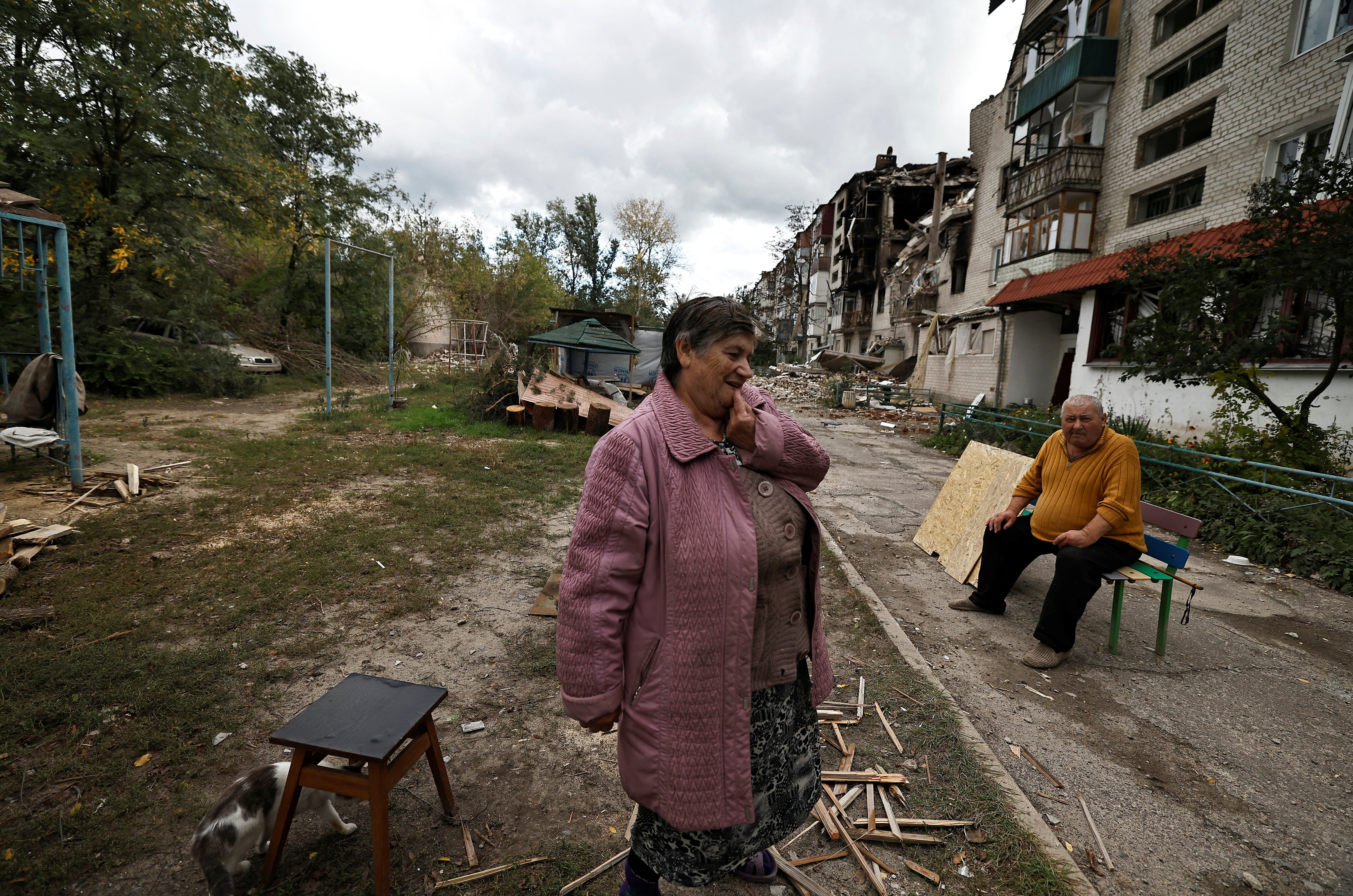 A woman reacts as she stands outside a building that was damaged by Russian missile in Svyatohirsk