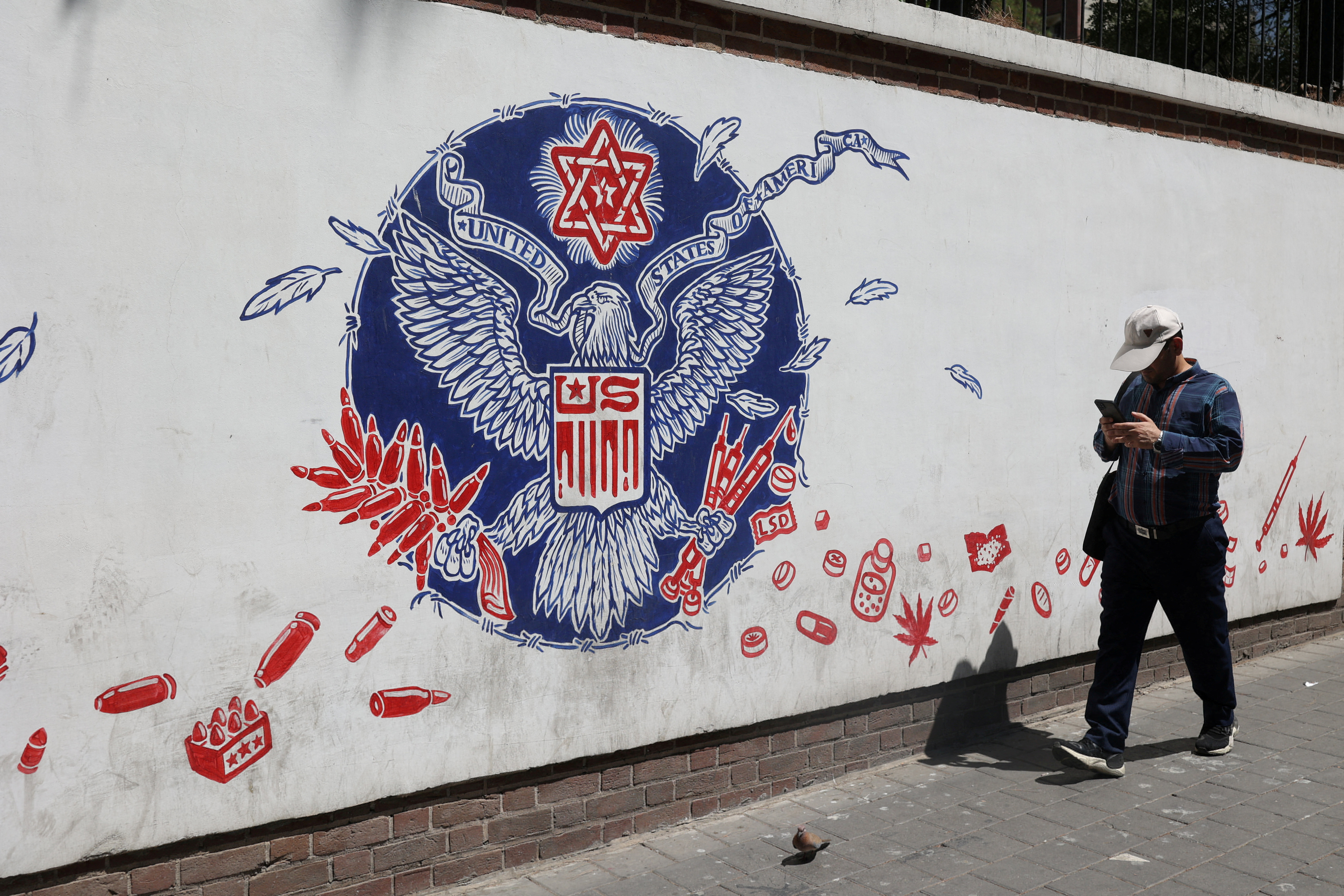 An Iranian man walks past a wall of the former U.S. Embassy, with an anti-America mural on it, in Tehran