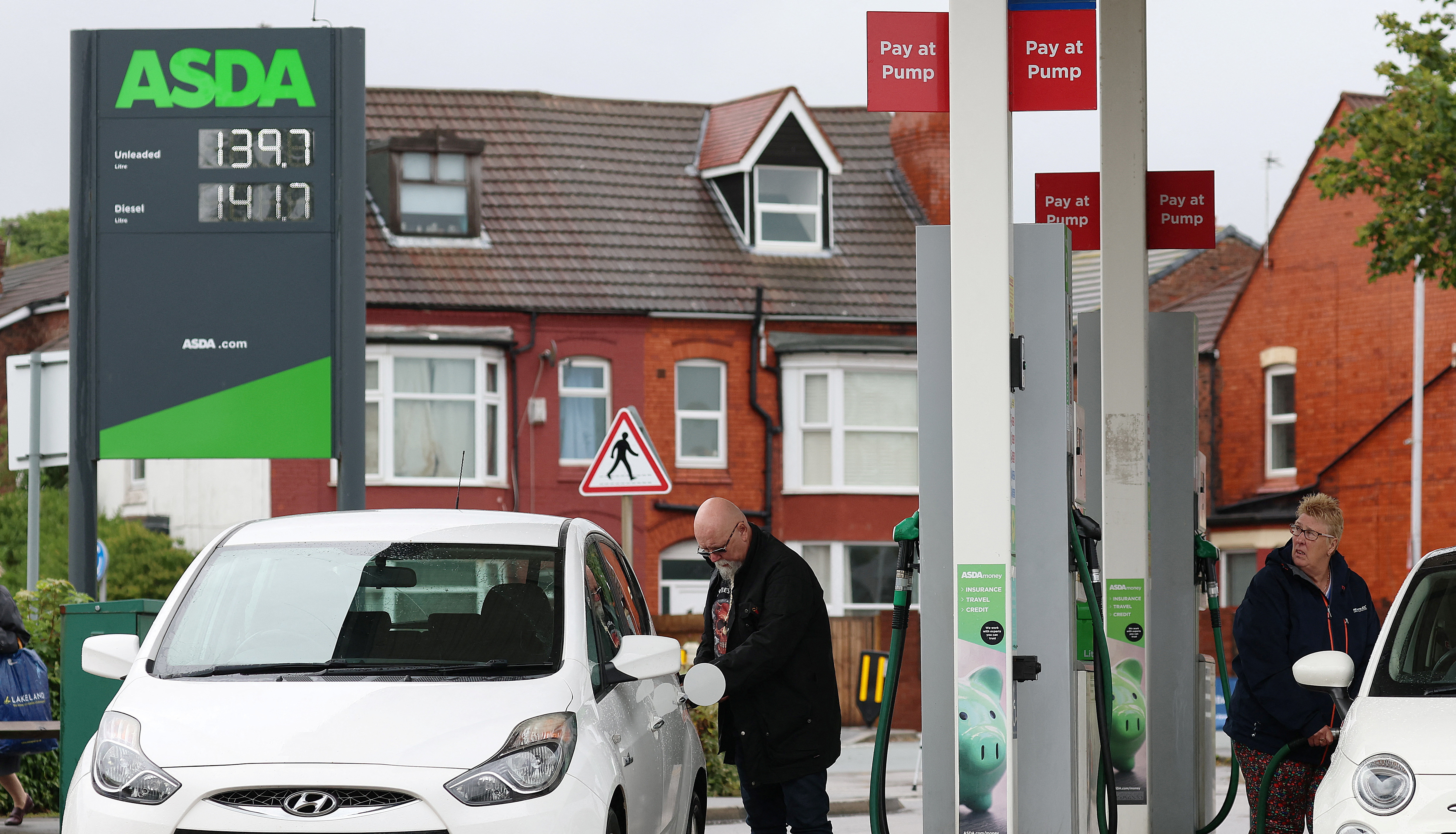 People put fuel in their cars at a filling station at an ASDA supermarket in Birkenhead, Britain