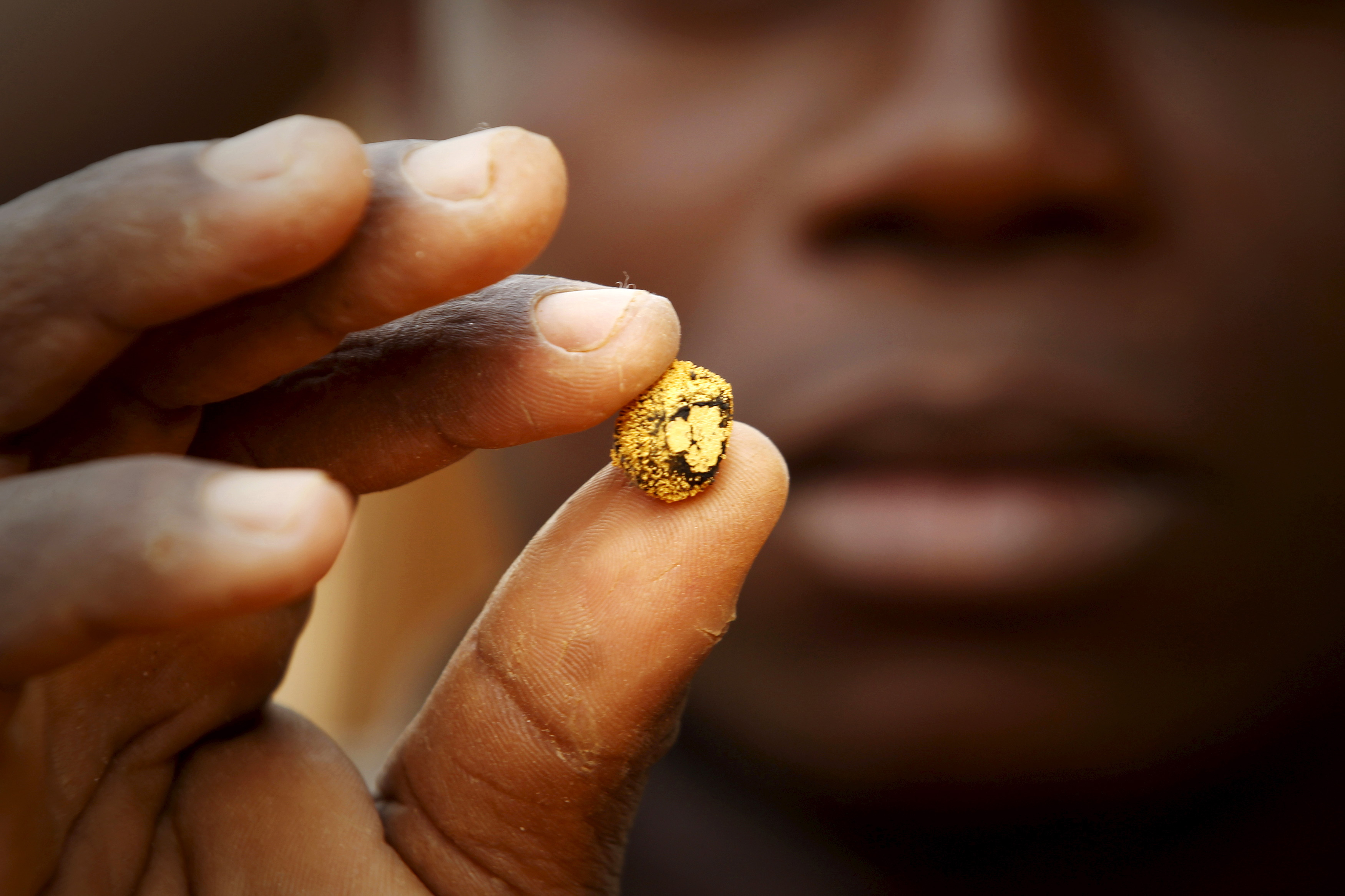 Gold prospector holds a gold nugget between his fingers at a gold mine near the village of Gamina in western Ivory Coast