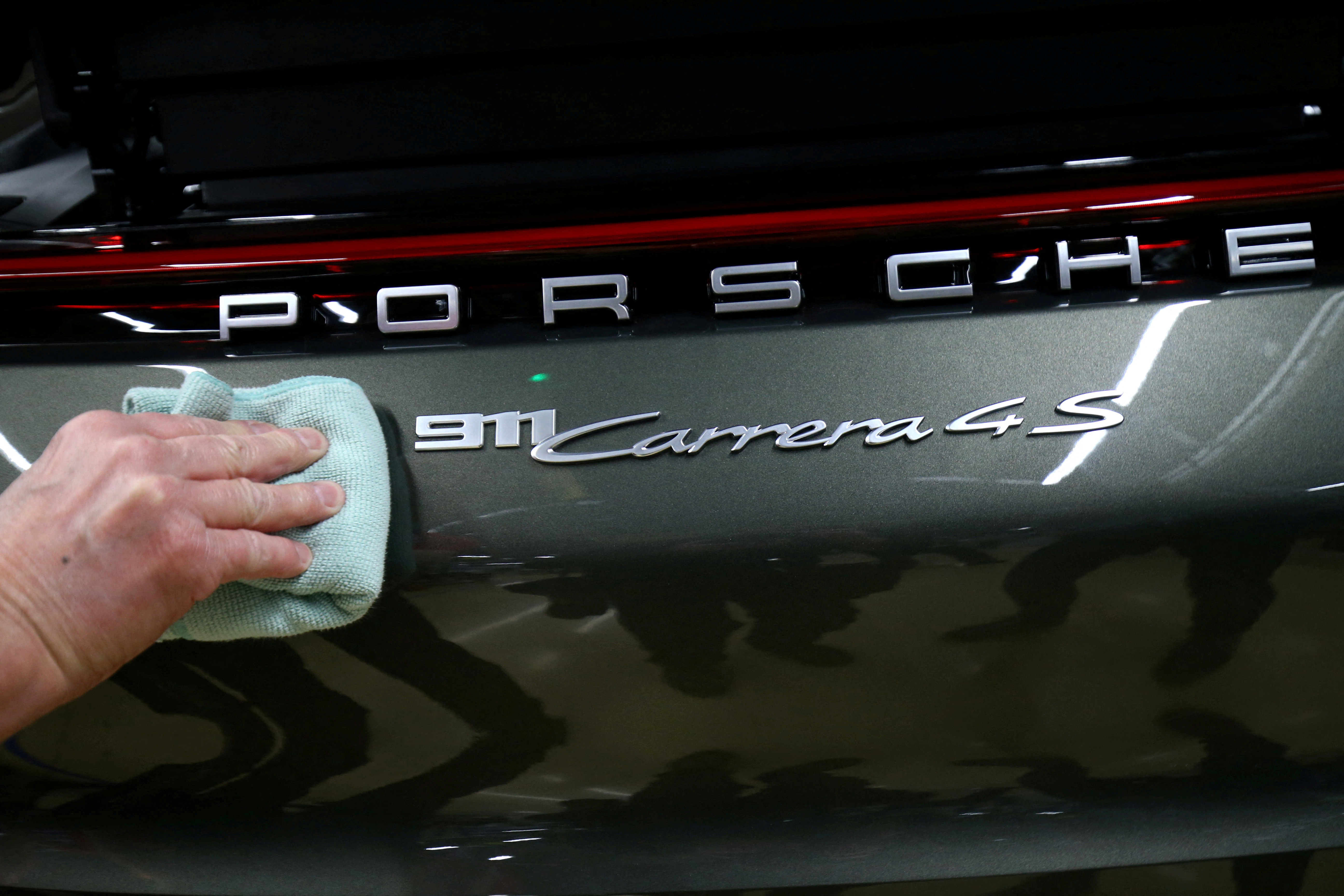 An employee of German car manufacturer Porsche fixes a Porsche 911 Carrera 4S label at the Porsche factory in Stuttgart-Zuffenhausen