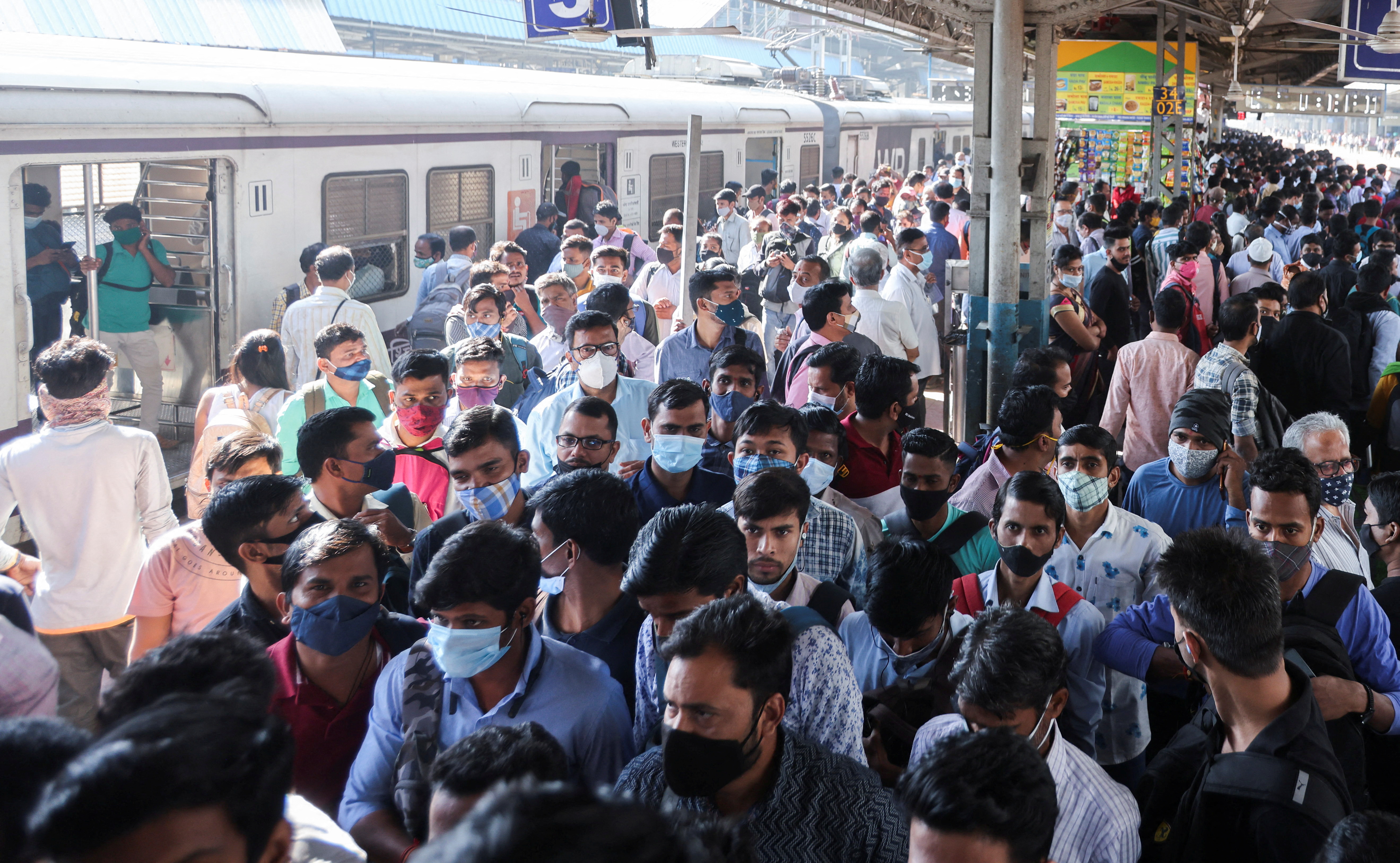 Commuters walk on a platform after disembarking from a train at a railway station in Mumbai