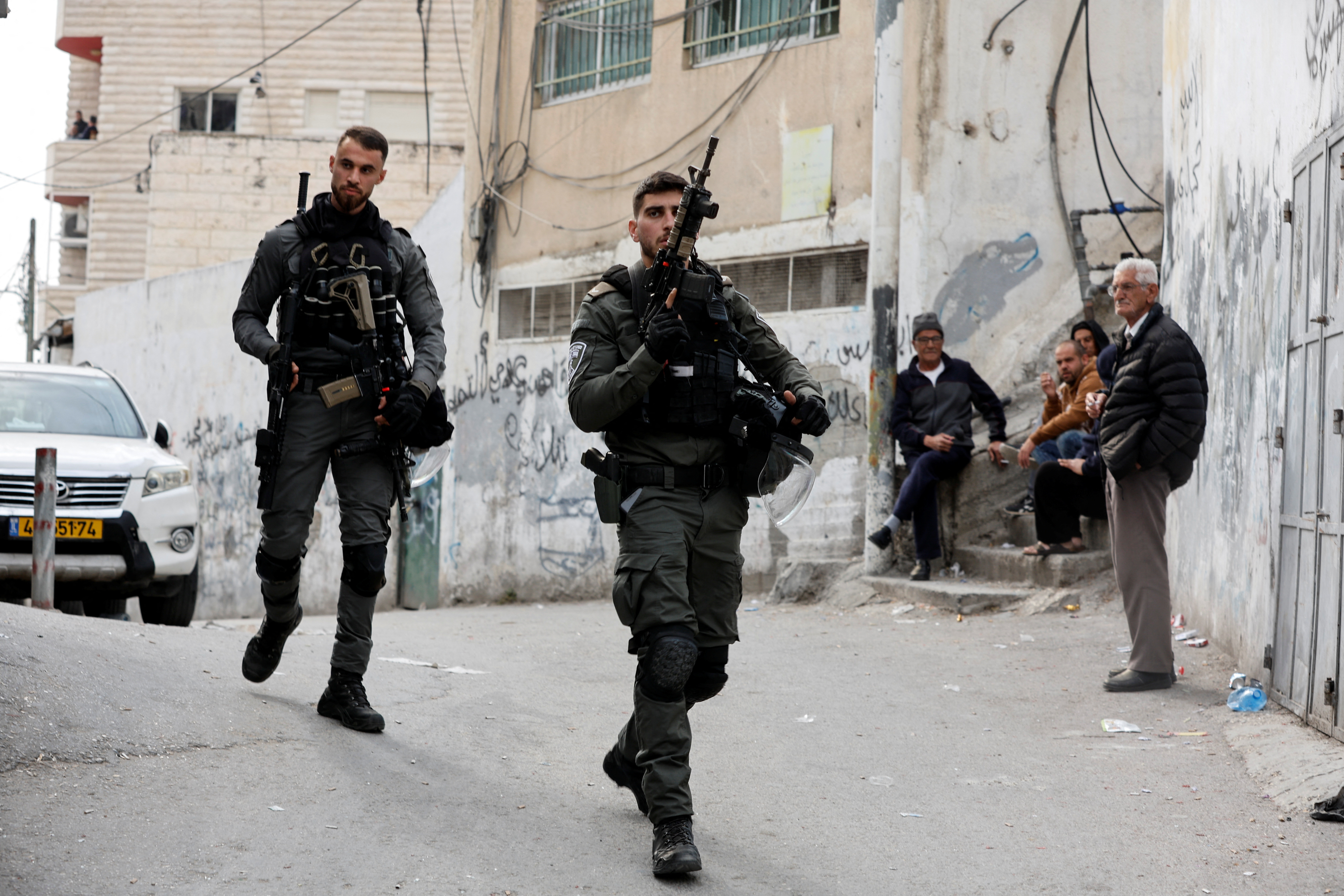 Israeli Border Policemen walk outside the home of Palestinian gunman Khair Alqam in the town of Al-Tur, East Jerusalem