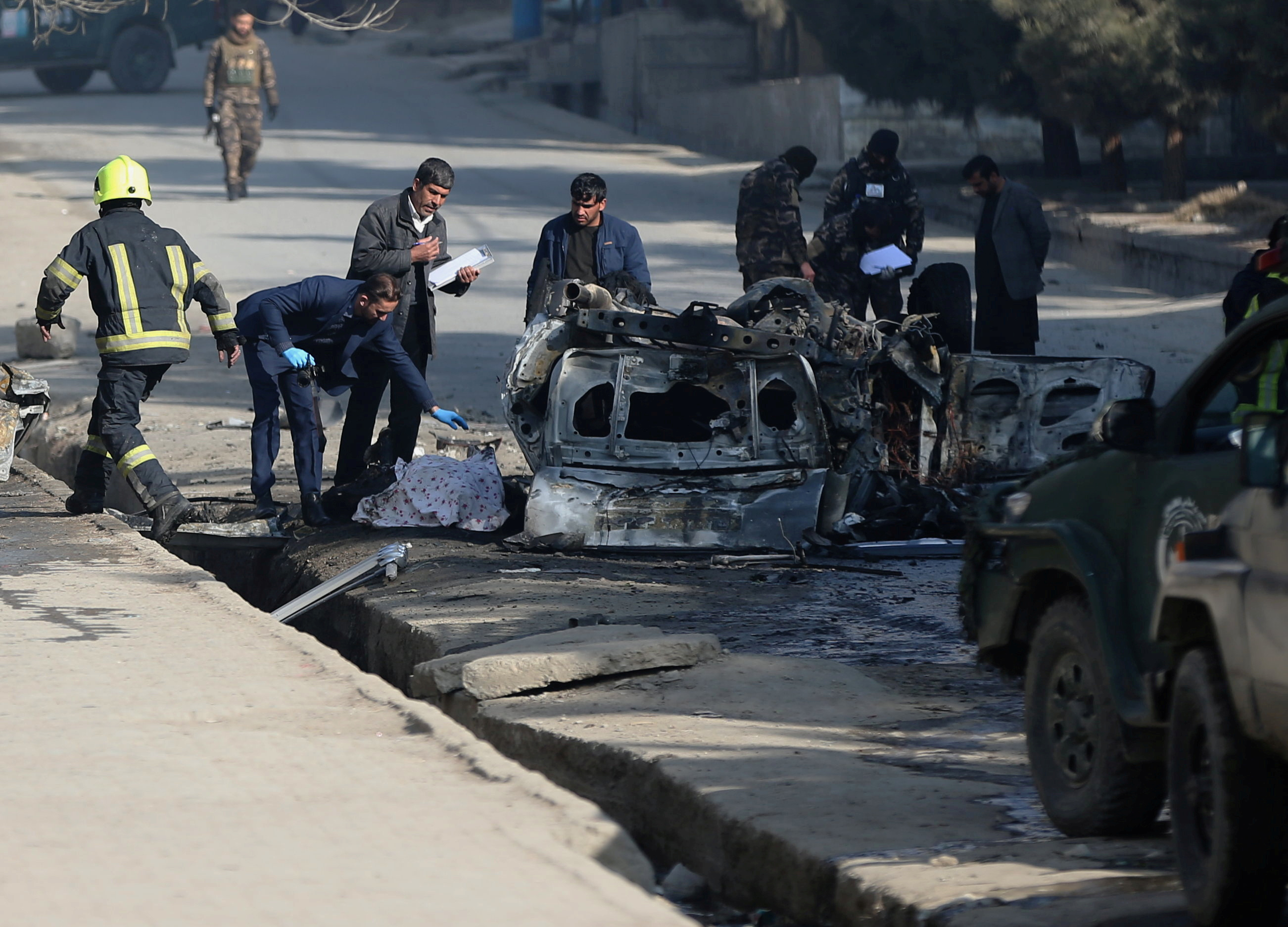 Afghan officials investigate at the site of a bomb blast in Kabul
