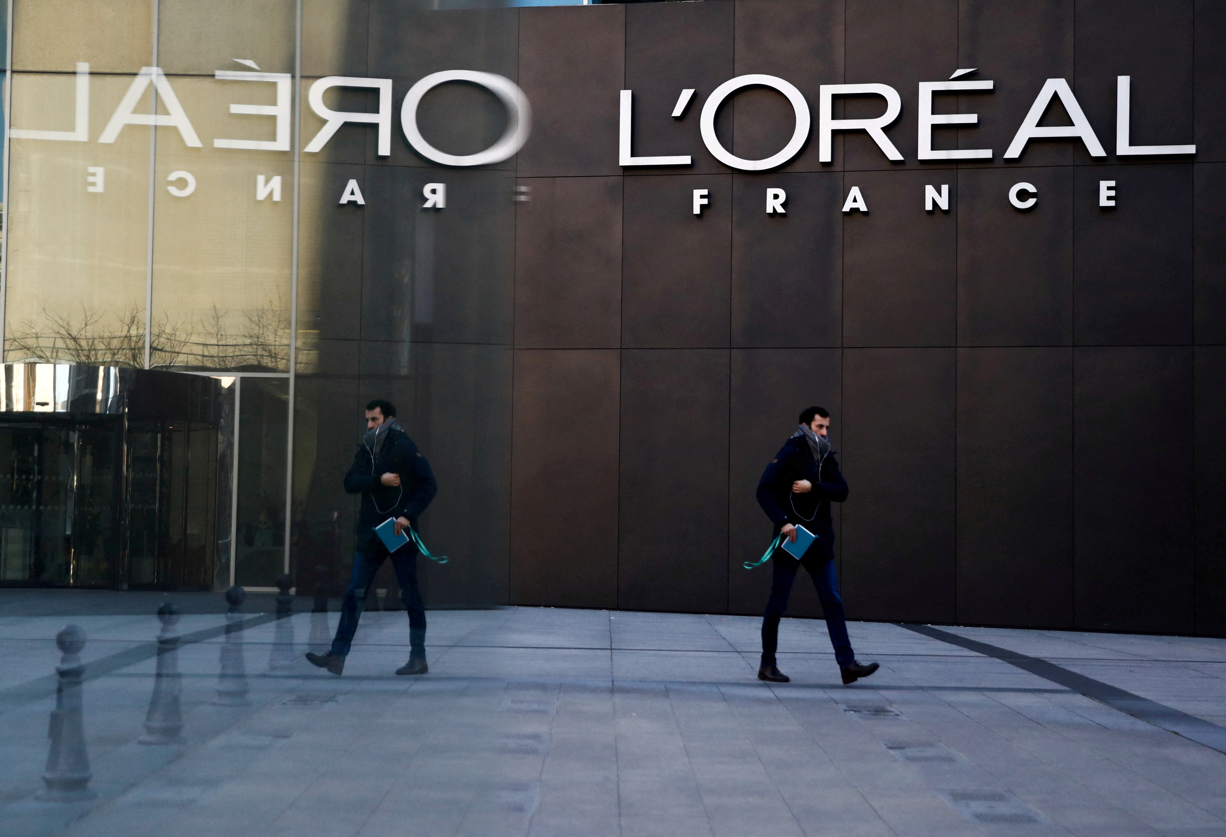A man walks by the logo of French cosmetics group L'Oreal in the western Paris suburb of Levallois-Perret
