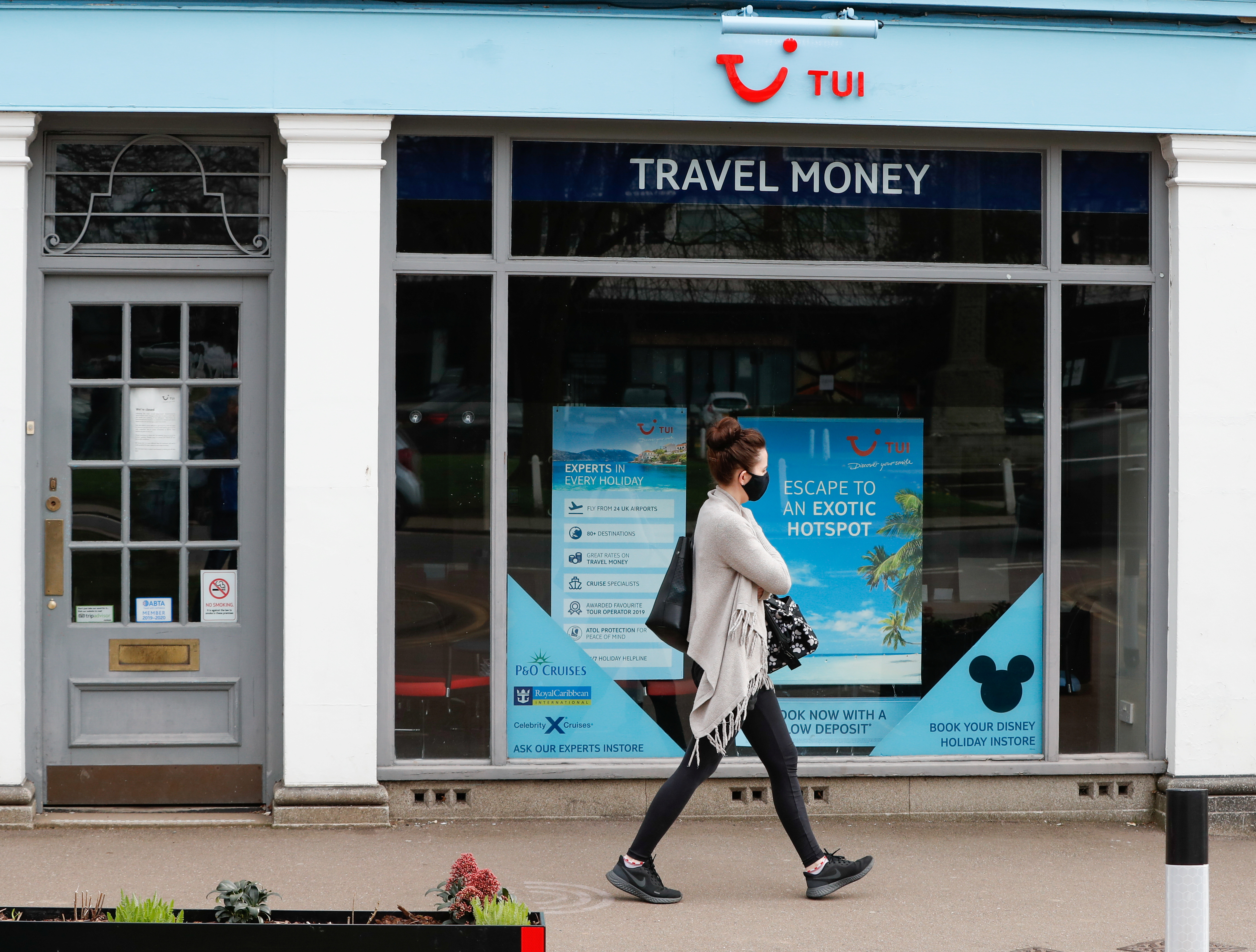 A woman walks past the TUI travel centre, amid the coronavirus disease (COVID-19) outbreak, in Harpenden, Britain, March 24, 2021. REUTERS/Paul Childs
