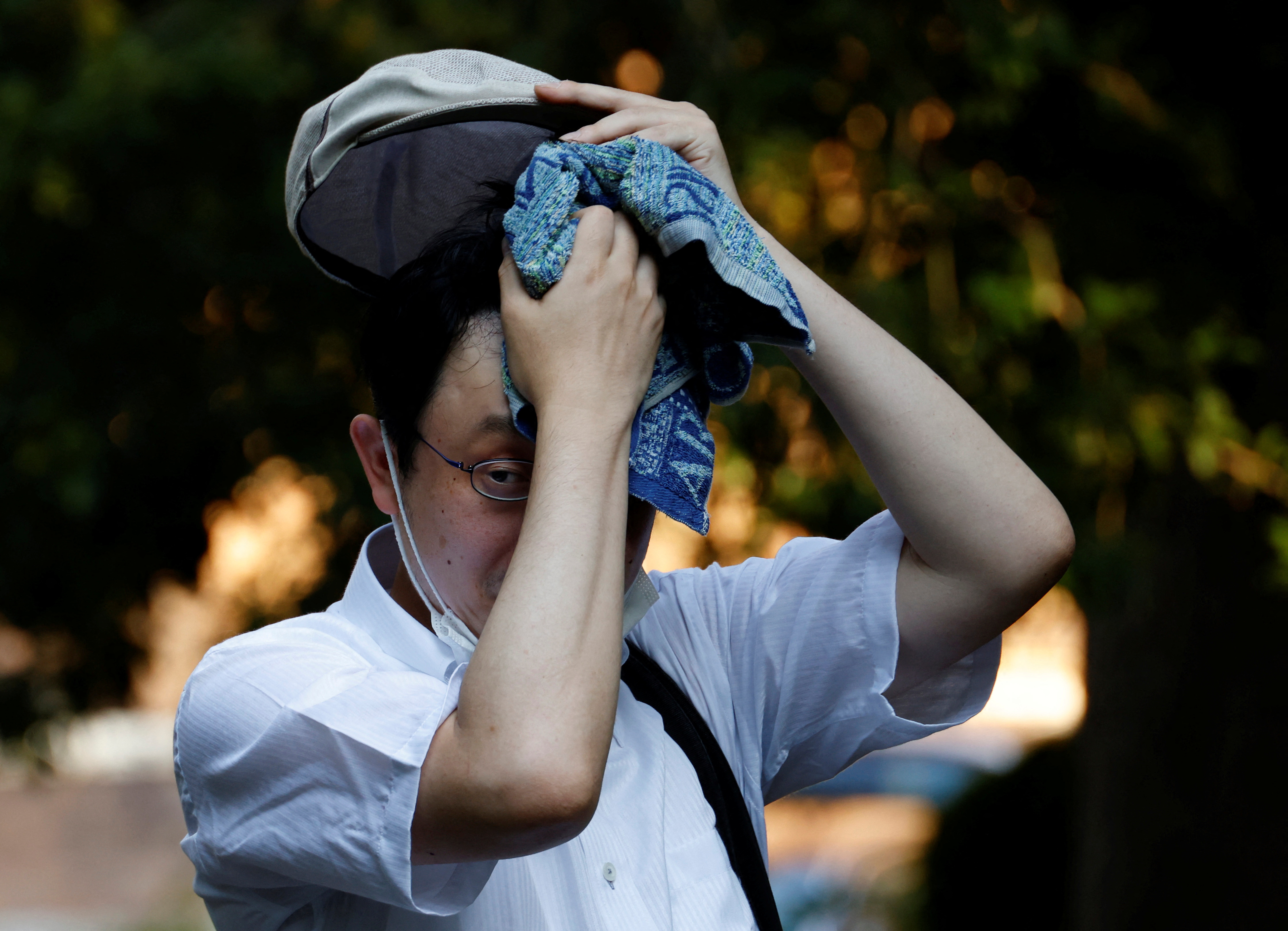 A man wipes off sweat with a towel at a park under the strain of Tokyo's hottest June streak since 1875 in Tokyo