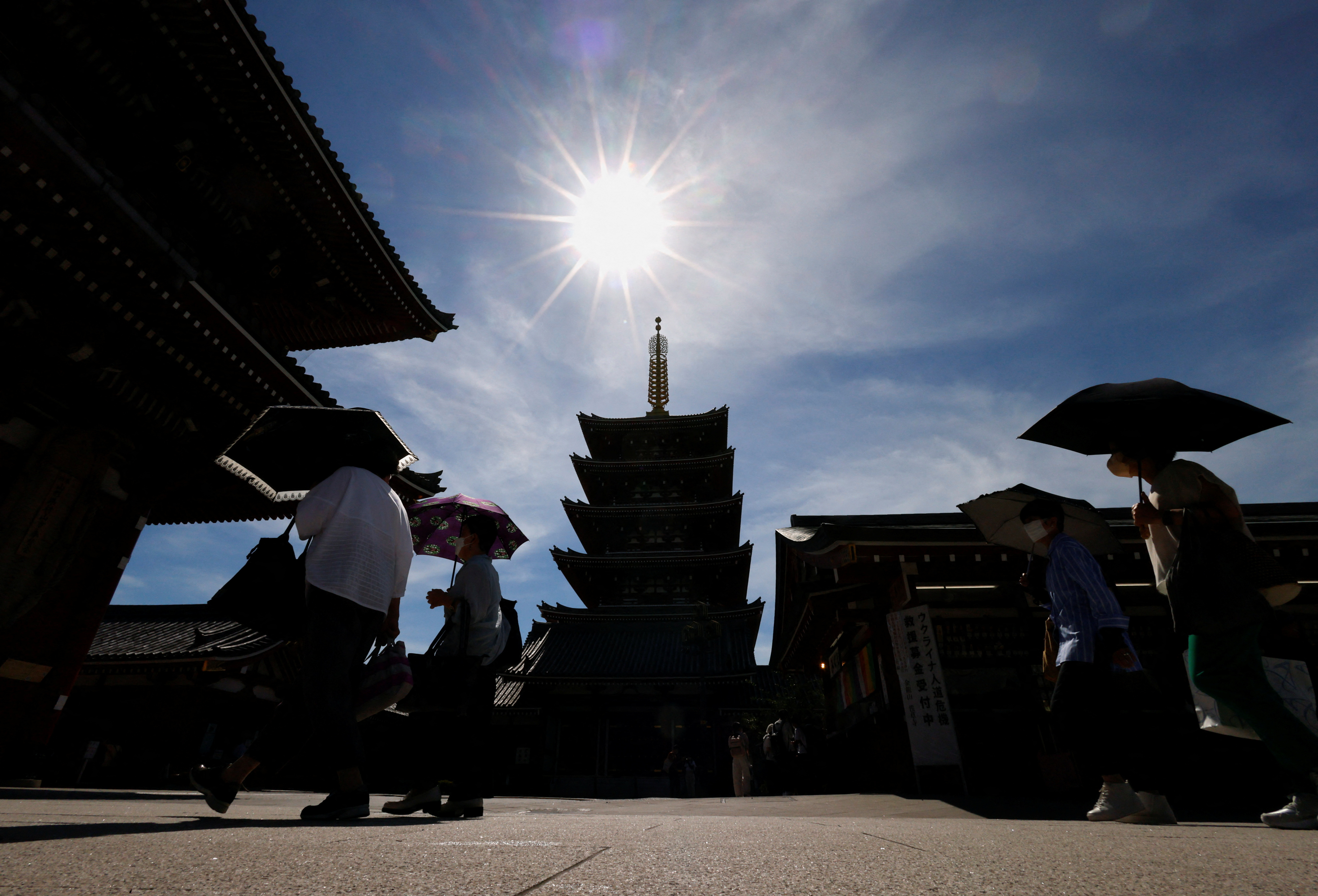 Visitors holding umbrellas stroll at Sensoji temple as Japanese government issues warning over possible power crunch due to heatwave in Tokyo